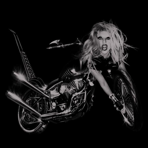 Lady Gaga in schwarzem Leder auf Motorrad, Schwarz-Weiß-Bild, neigt sich zur Kamera.
