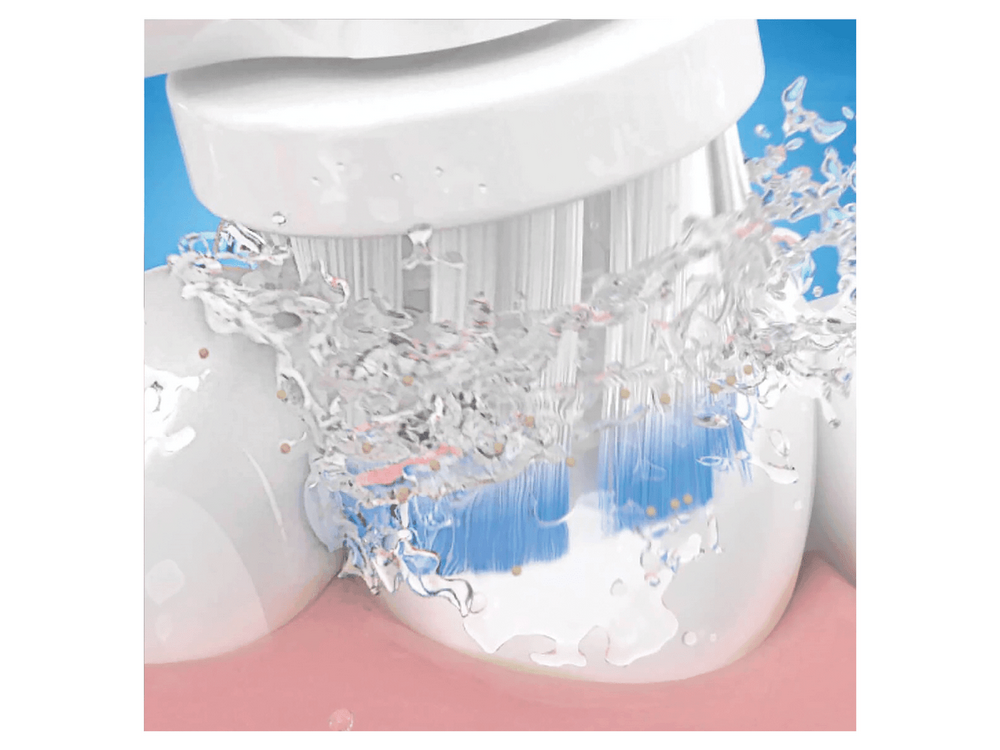 Primer plano de un cepillo de dientes eléctrico limpiando dientes, con spray de agua y cerdas azules.