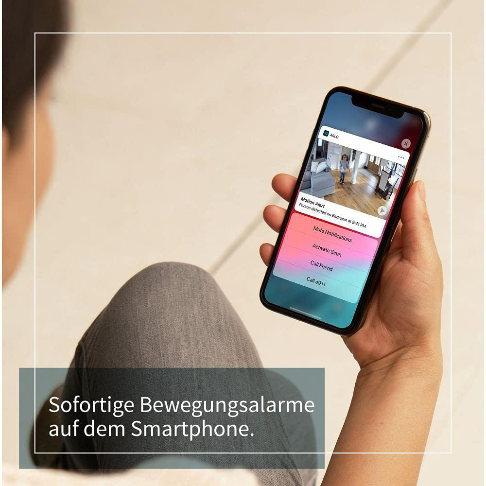 Eine Person hält ein Smartphone mit einer Home-Security-App und Benachrichtigungen.