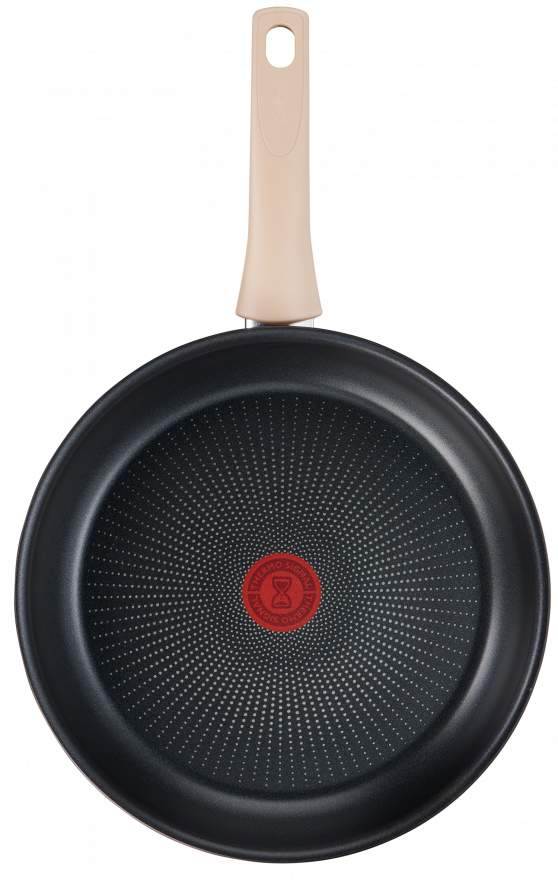 Top view of a black frying pan with a beige handle, red center, and a dotted surface.