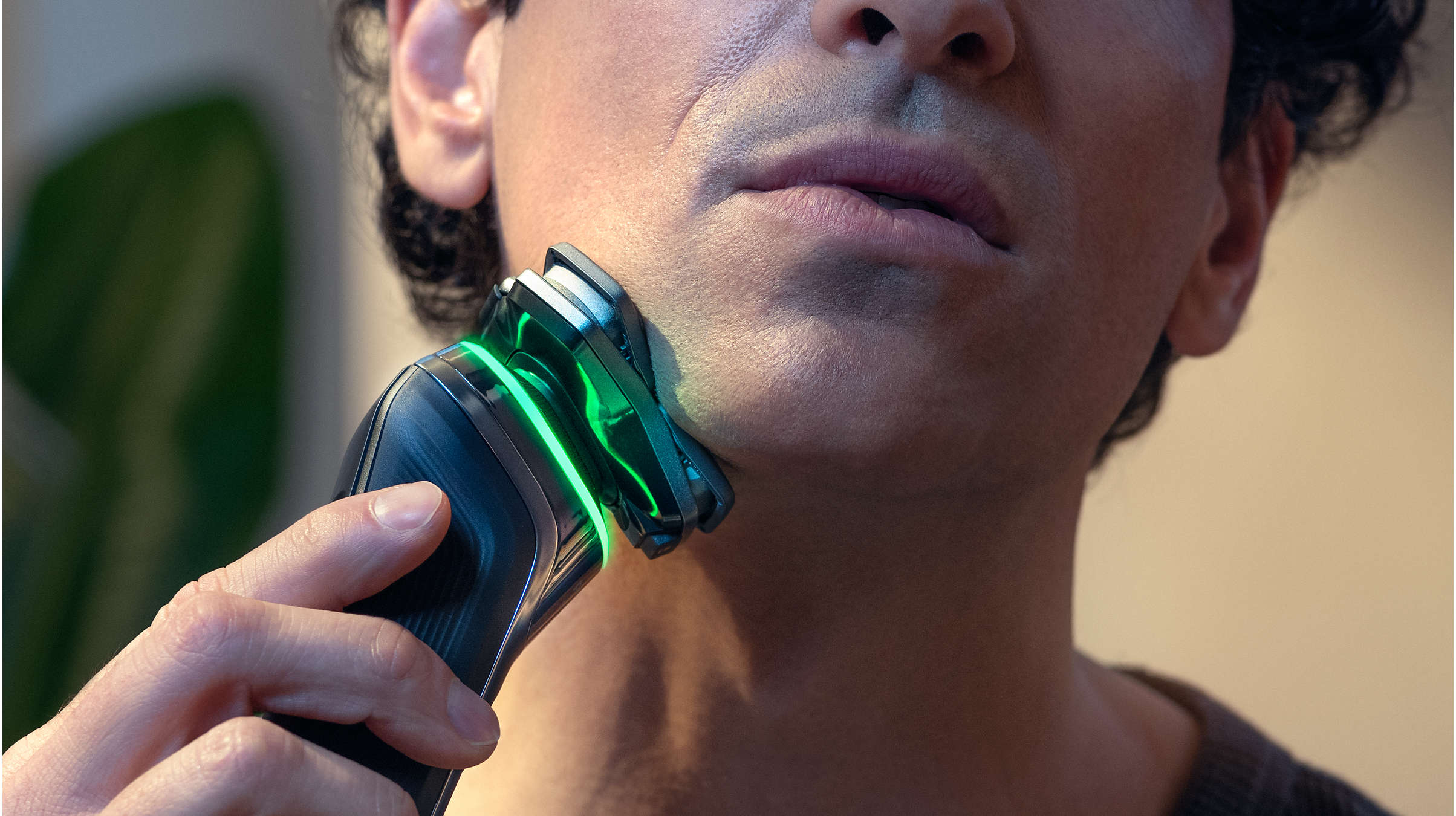 Mann rasiert sich mit Trimmer, grünes Licht sichtbar.