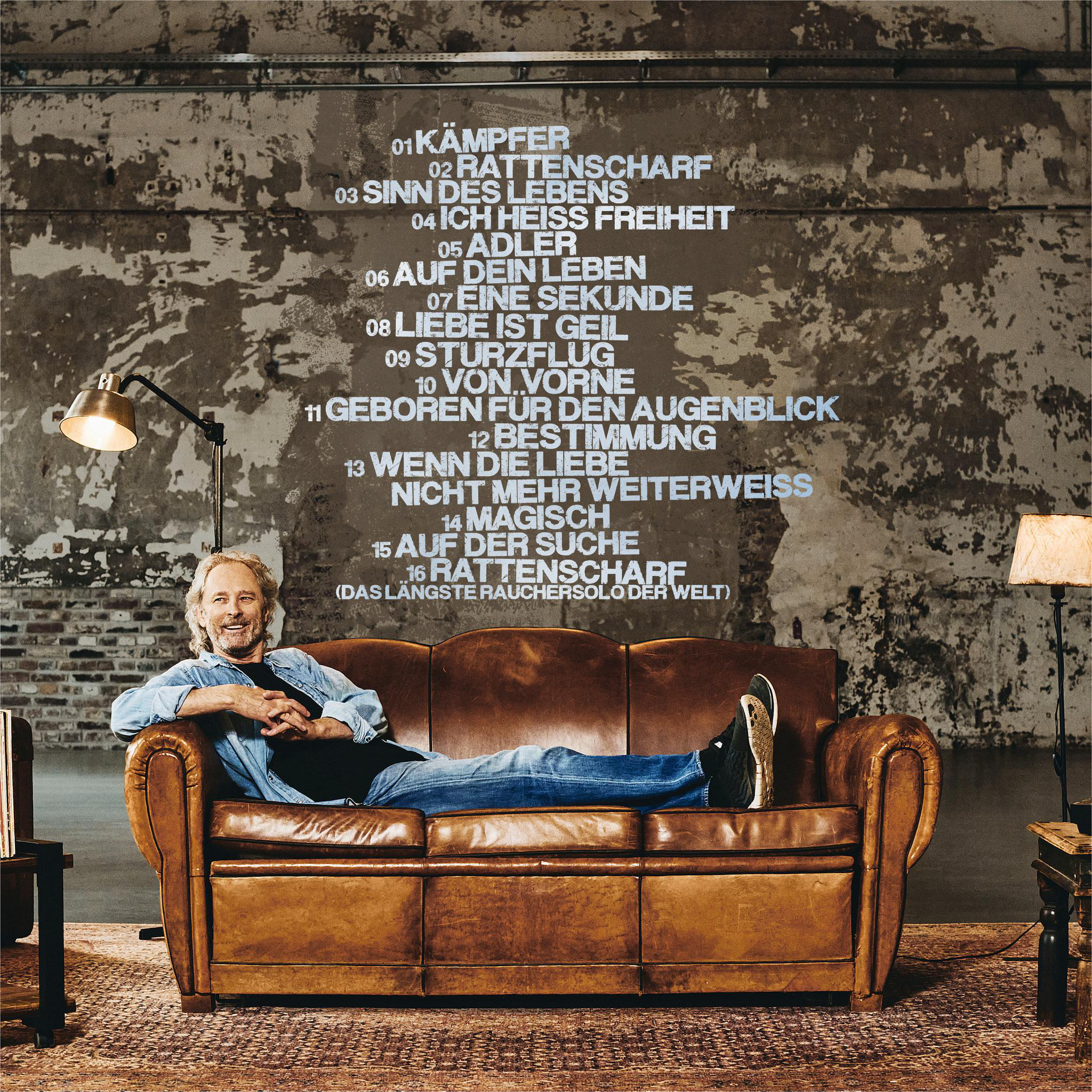 Mann auf braunem Sofa mit Texten an der Wand in einem schwach beleuchteten Raum.