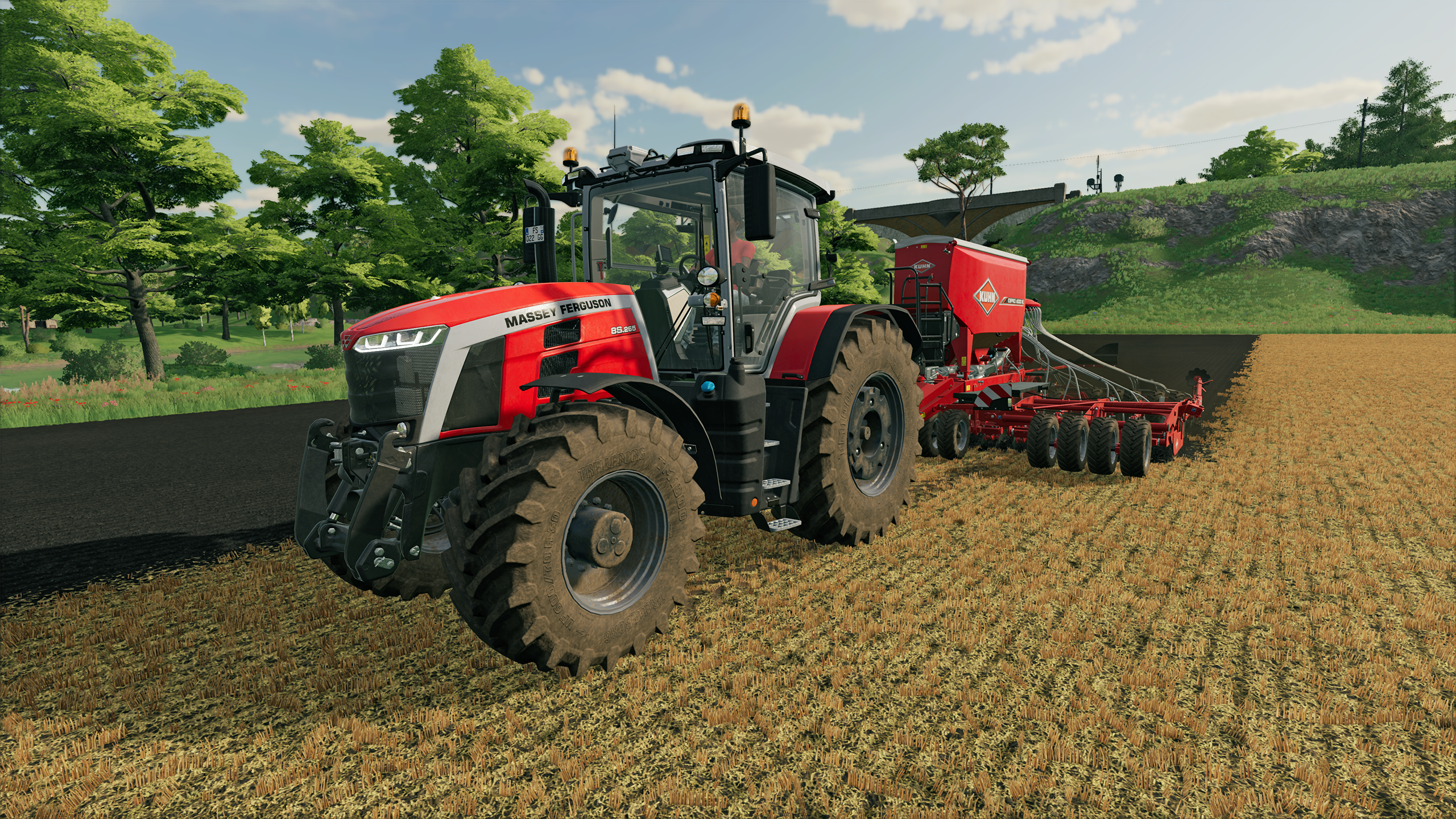 Roter Massey Ferguson Traktor mit Kuhn Sämaschine auf einem Feld, sonniger Tag.