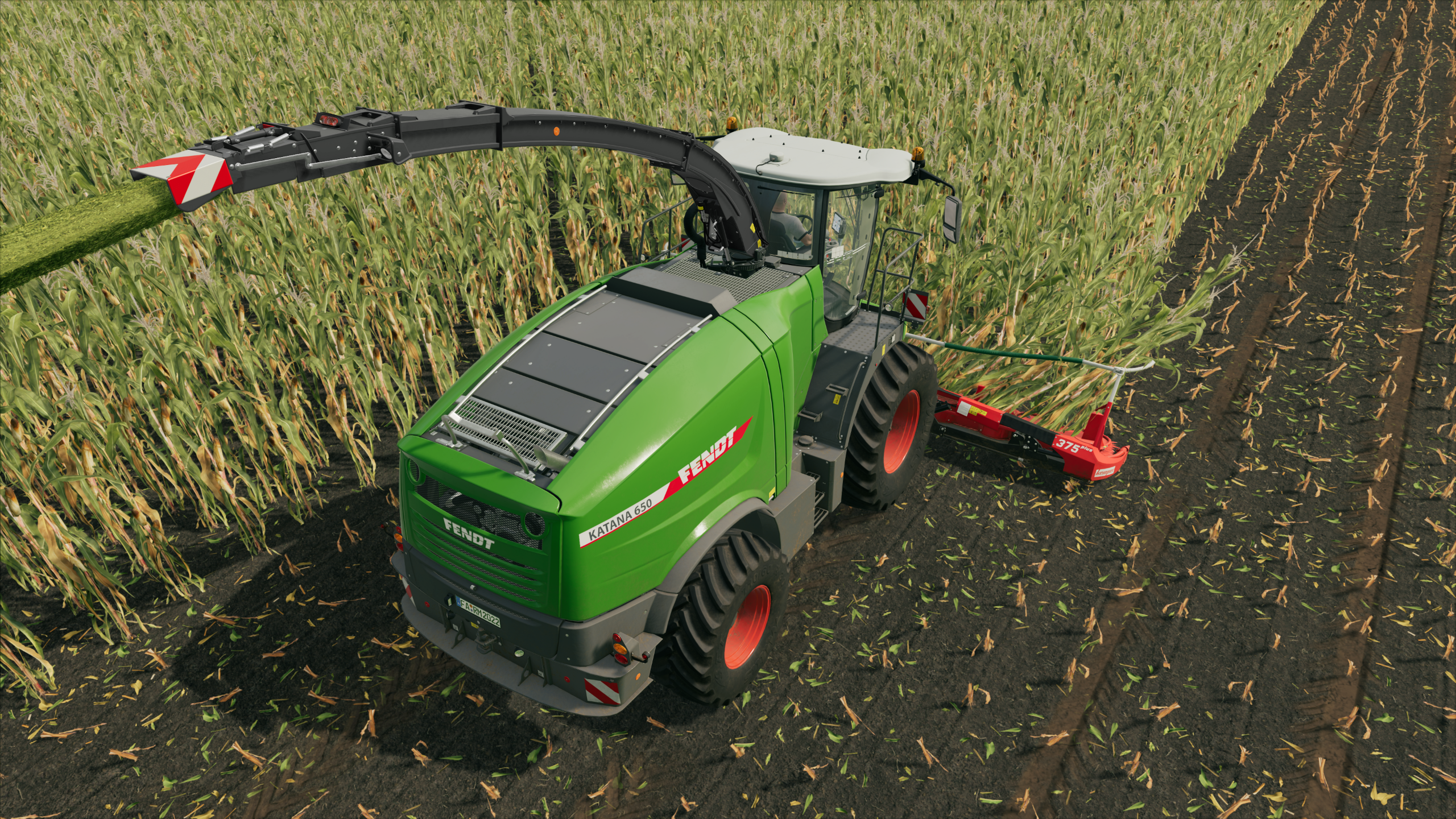 Ein grüner Fendt Katana 650, ein großes landwirtschaftliches Fahrzeug, erntet Feldfrüchte.