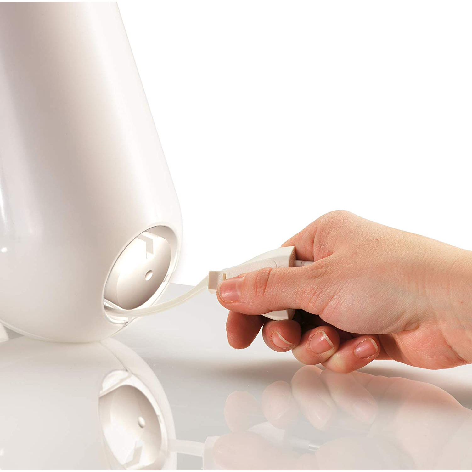 Una mano inserisce un cavo bianco nella base di un dispositivo bianco.