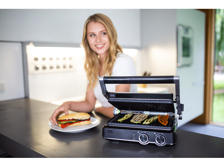 Nő szendviccsel, grill zöldségekkel. Konyhai környezet.
