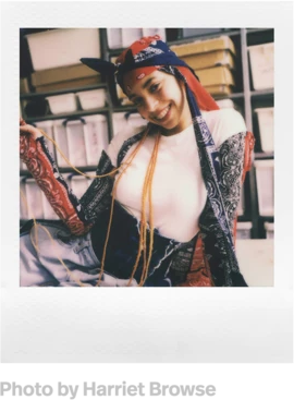 Polaroidfoto einer lächelnden Frau in Kopftuch, Hemd und Halskette.
