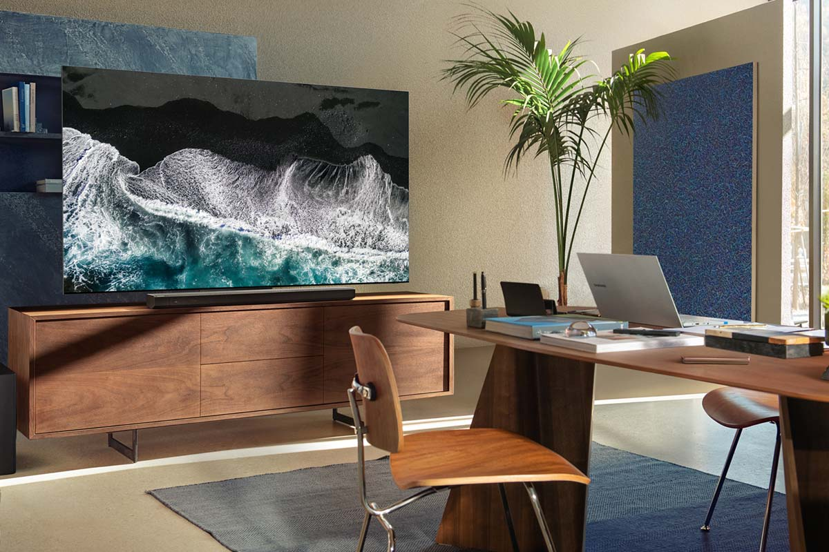 Salón con TV, escritorio, silla y plantas, brillante y moderno.