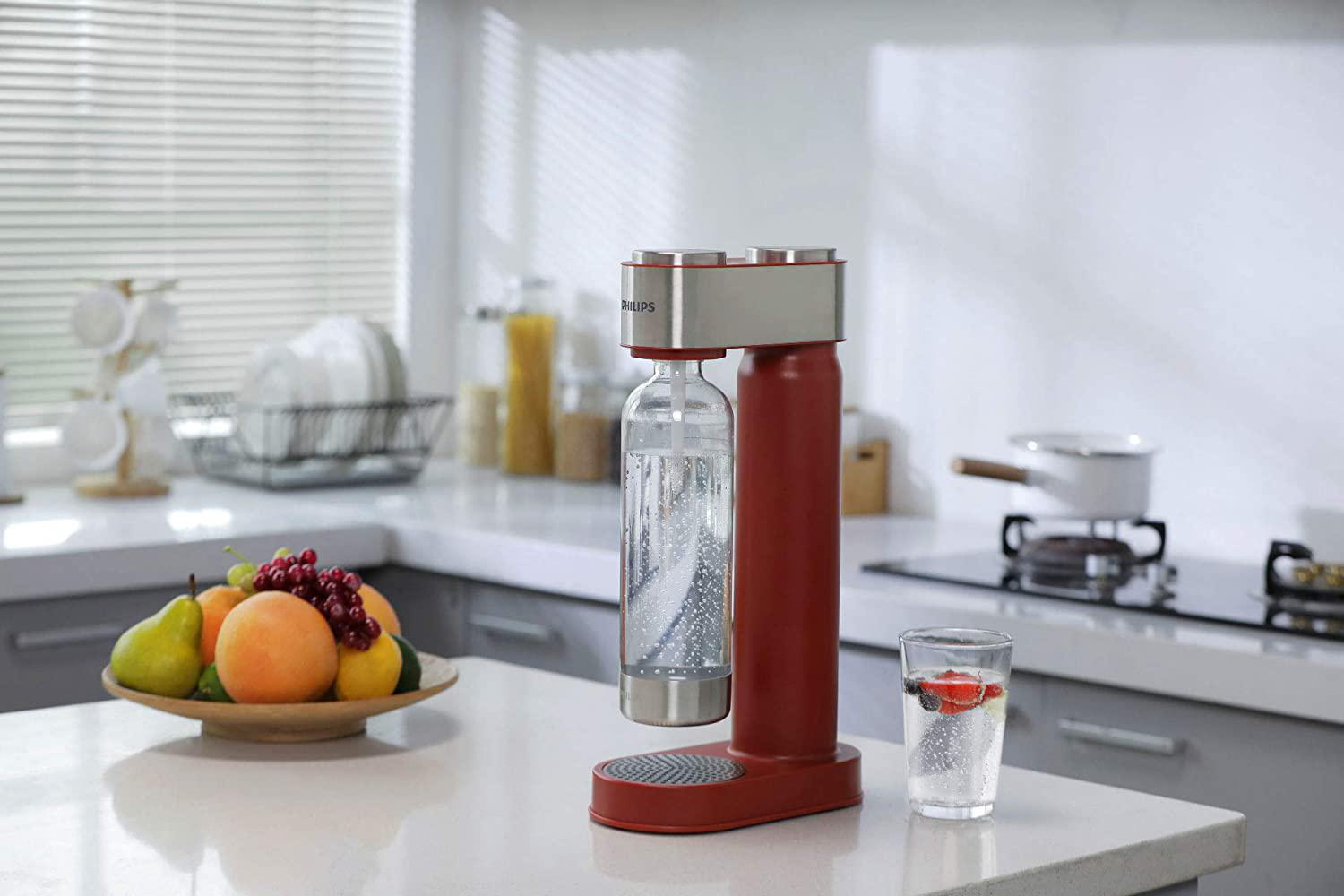 Küchenszene mit rotem Wassersprudler und einem Glas Wasser mit Obst.