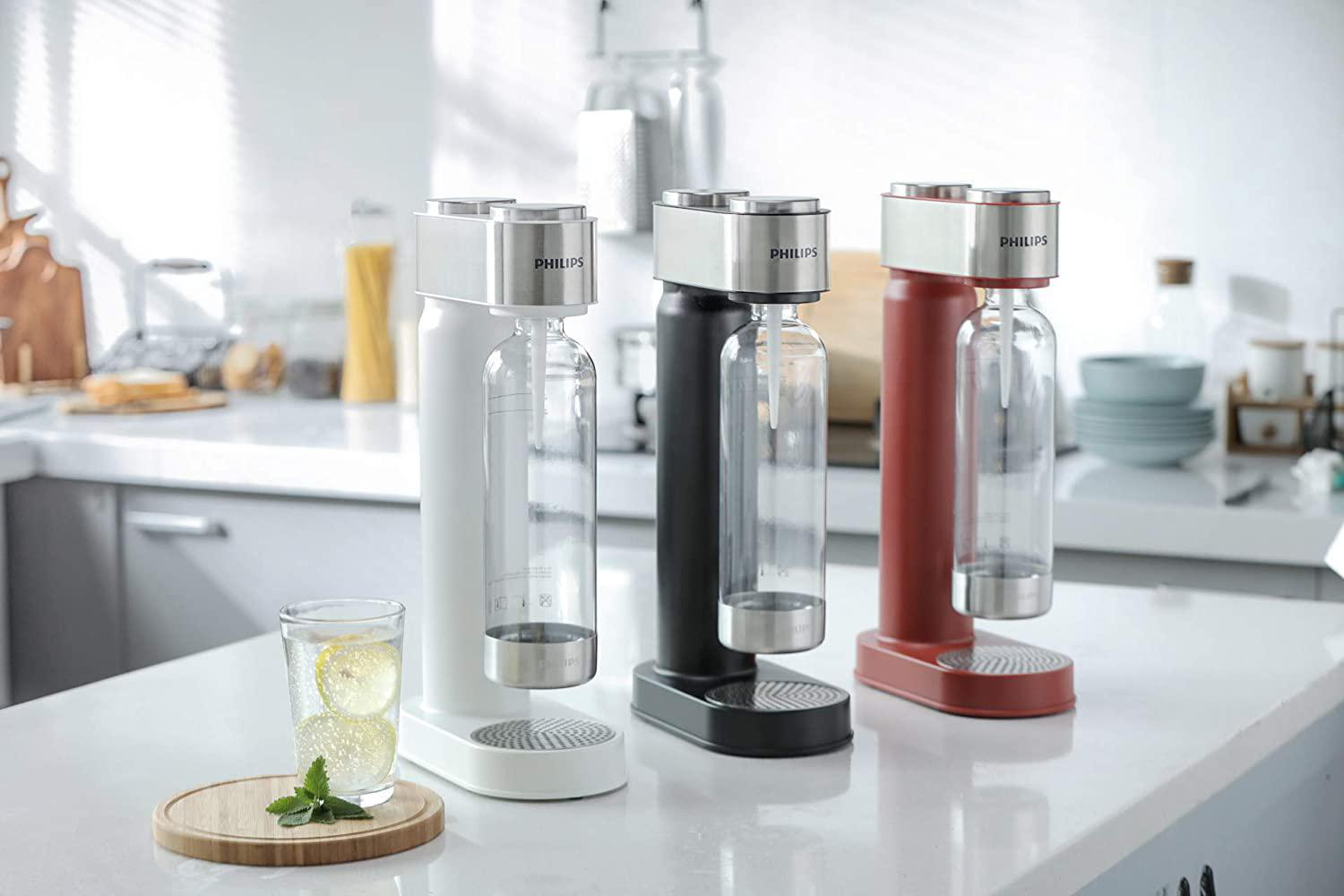 Drei Soda Maker. Weiß, schwarz und rot. Glas Wasser mit Zitrone.