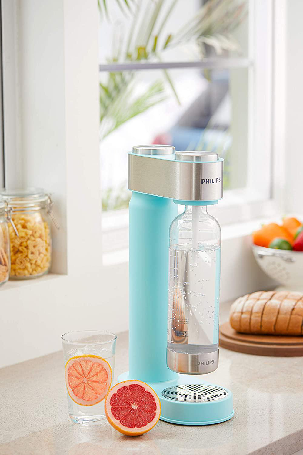 Eine SodaStream-Maschine mit einem Glas Grapefruitwasser und einer halben Grapefruit.