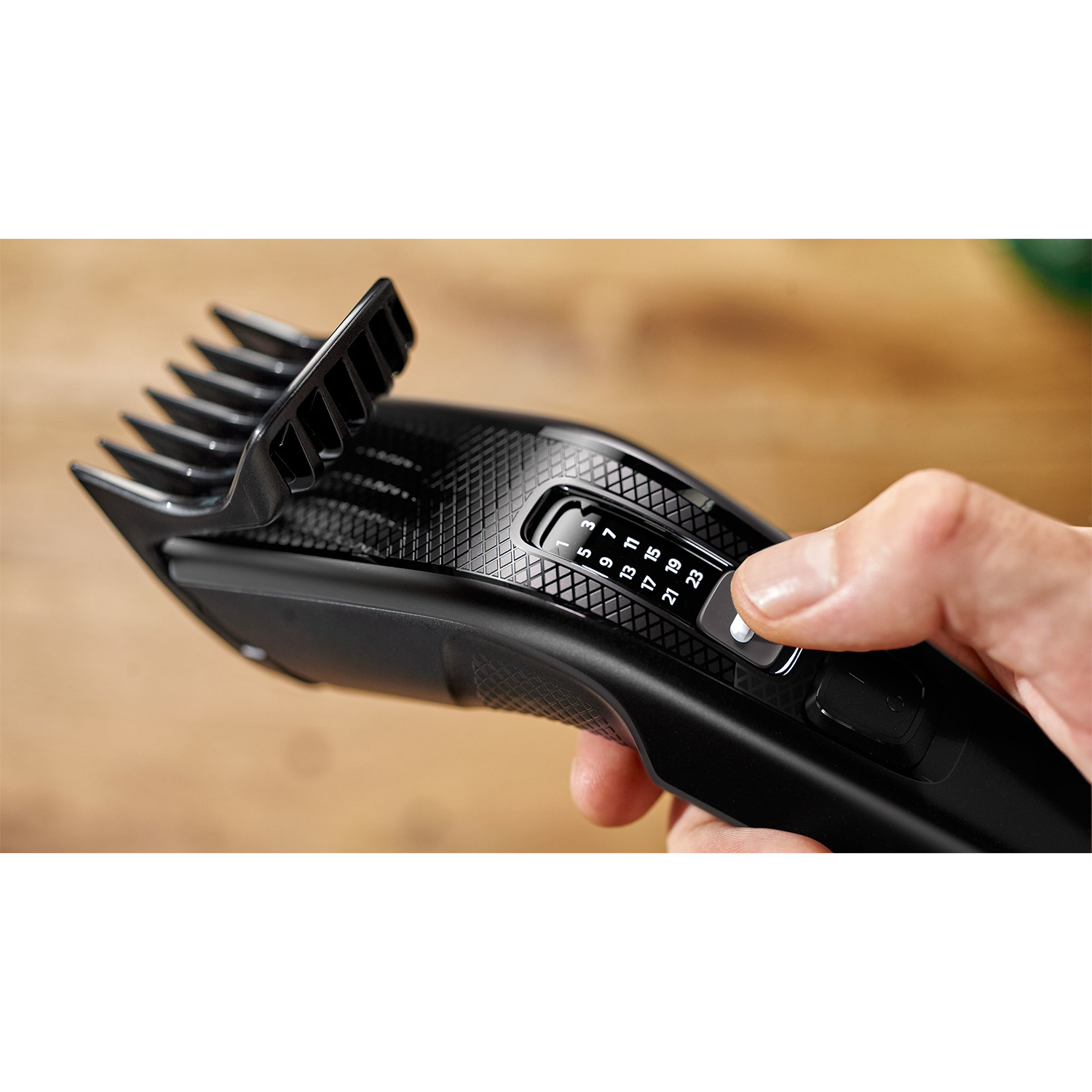 Tagliacapelli Philips nero con una mano che regola la lunghezza del taglio.