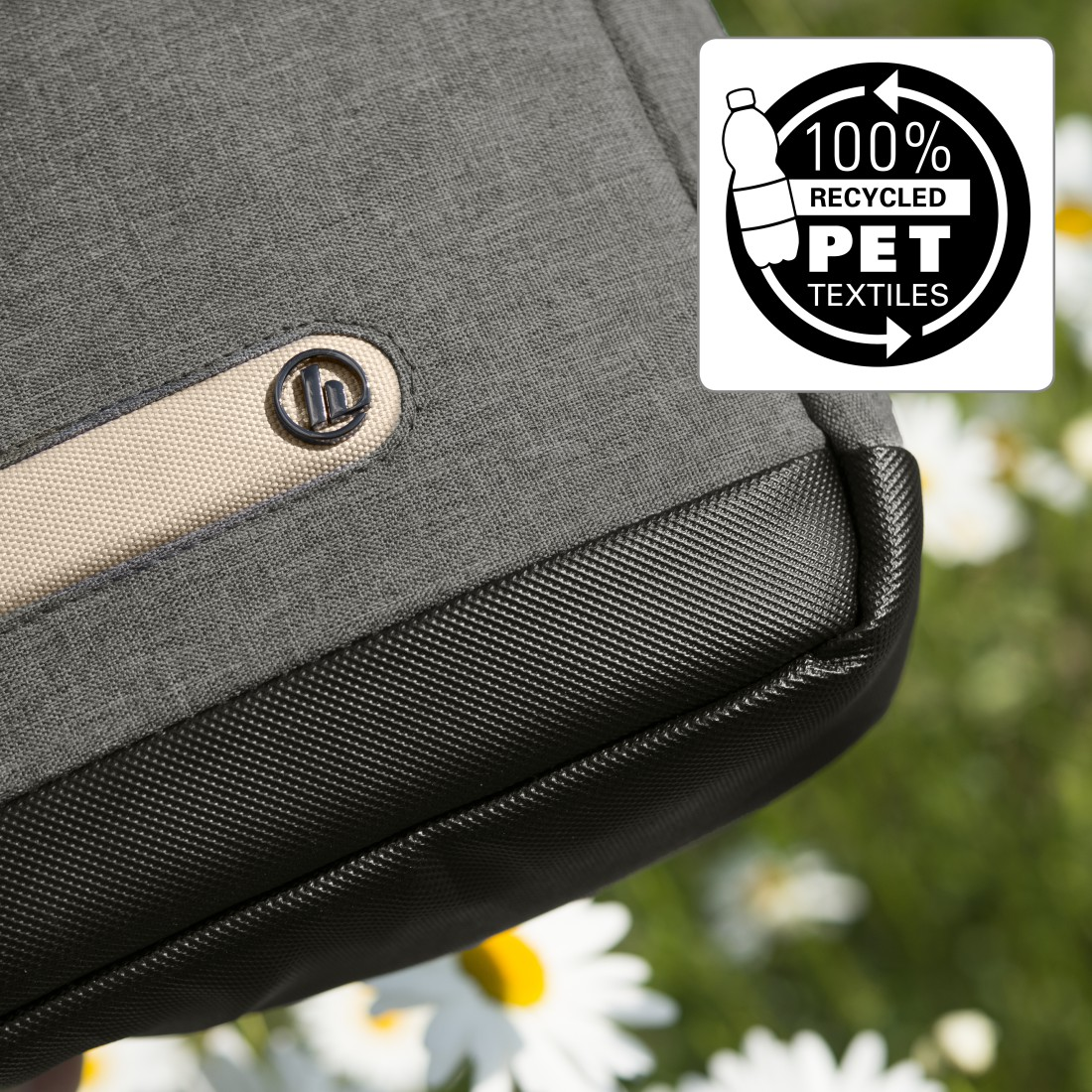 Nahaufnahme einer grauen Tasche mit schwarzem Boden und weißem Label für recycelte PET-Textilien.