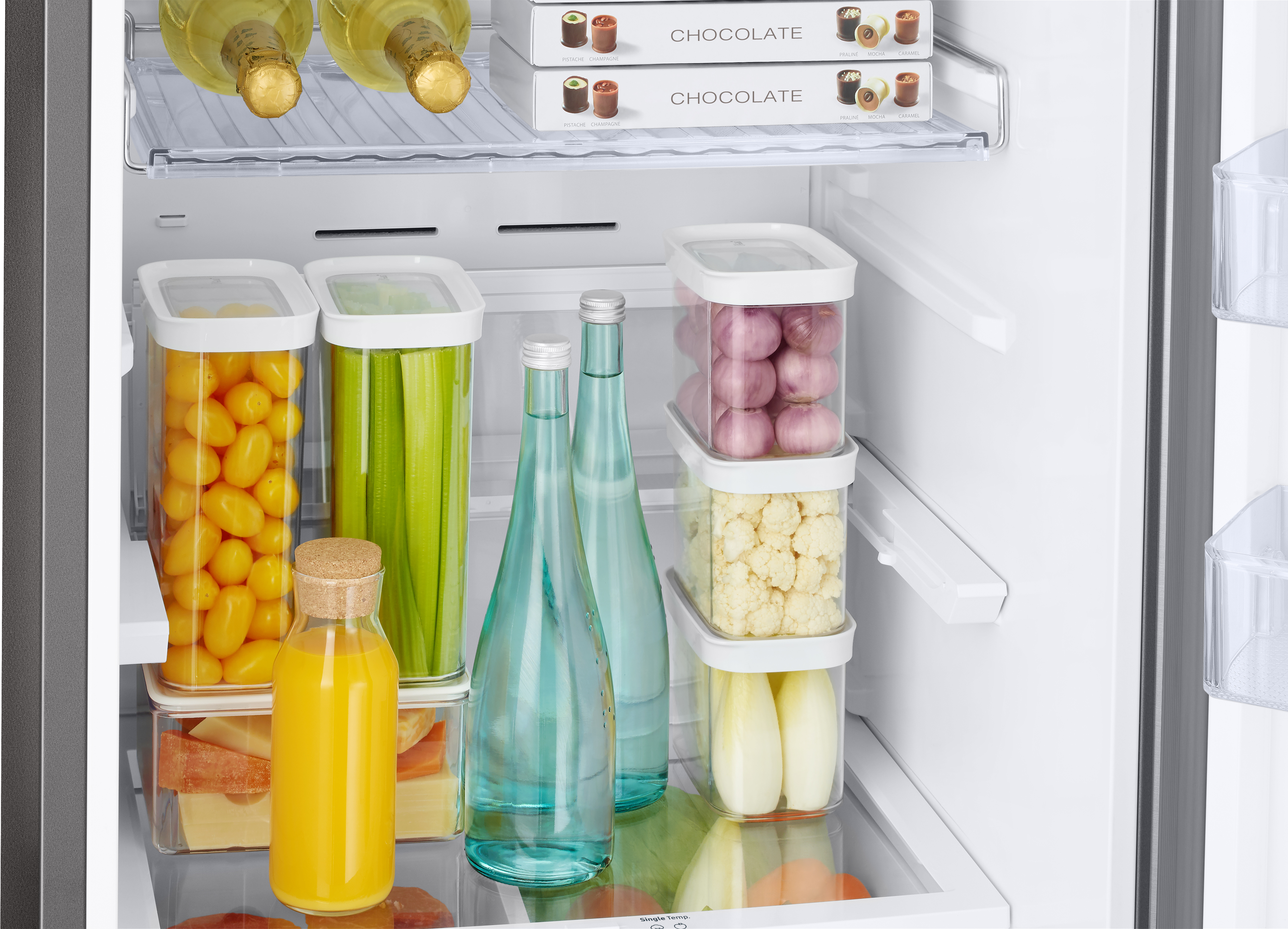 Im Kühlschrank: Flaschen, Behälter mit Lebensmitteln wie Tomaten und eine Flasche Saft.