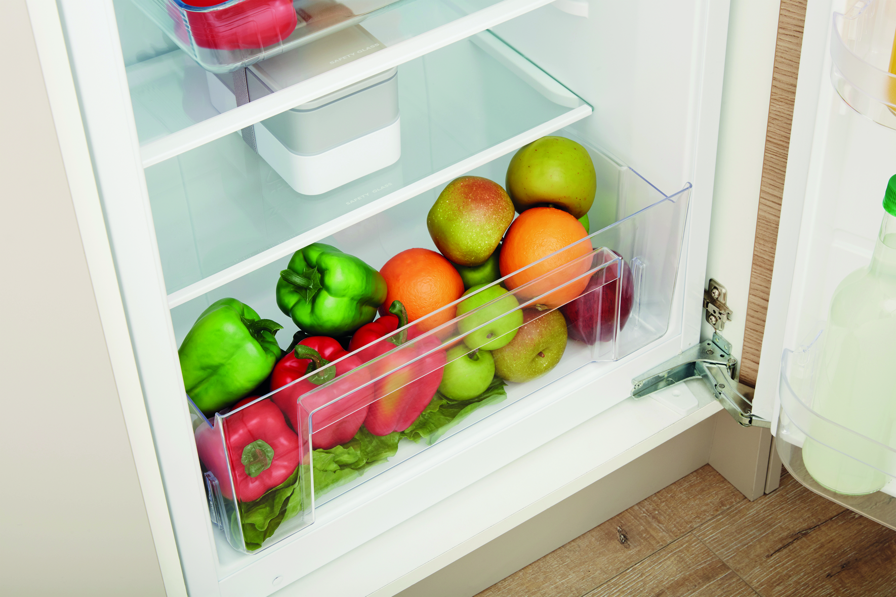 Kühlschublade: Gemüse, Obst und ein durchsichtiger Kunststoffbehälter.