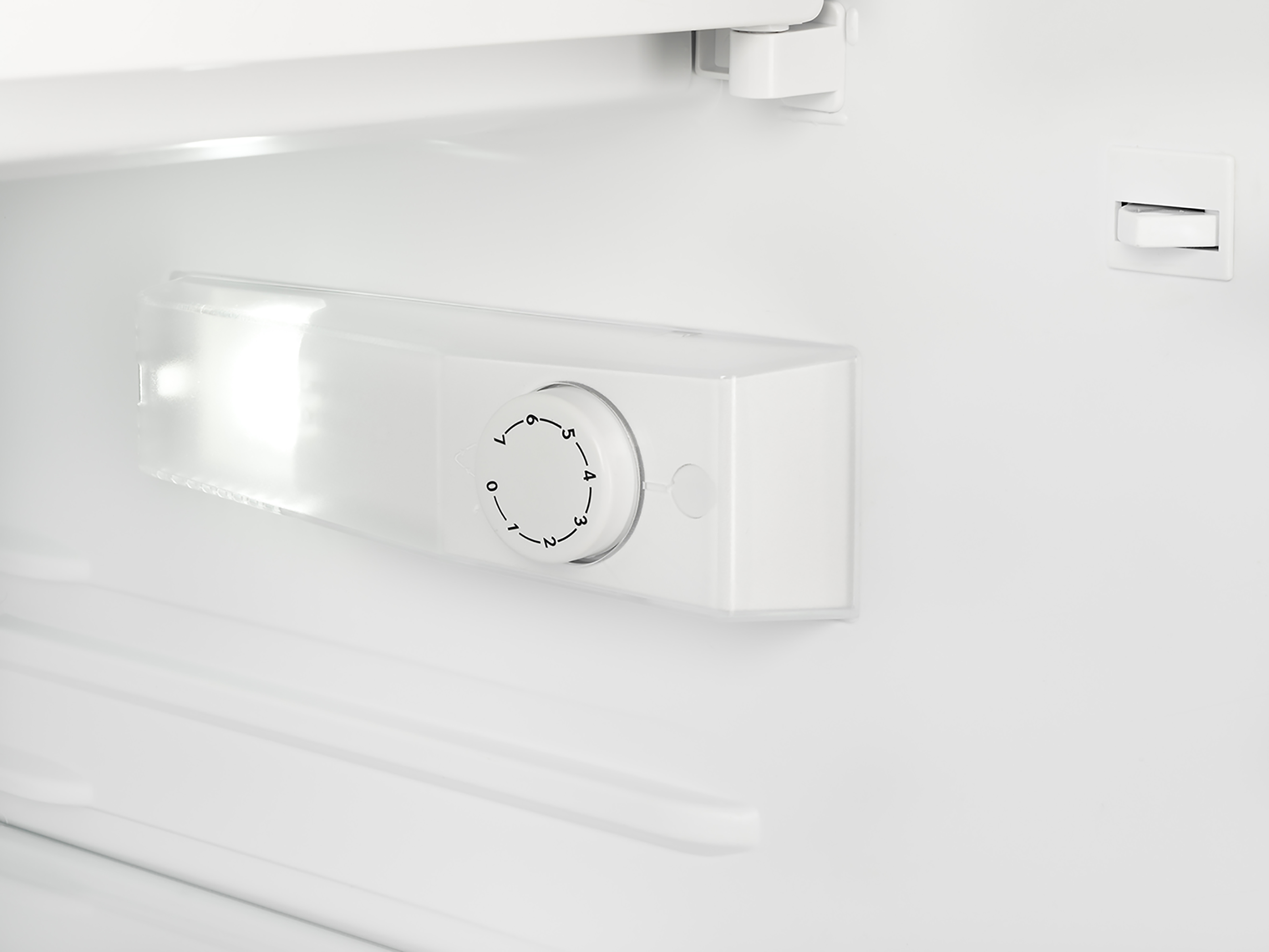A close-up view of the temperature control inside a white refrigerator. It has numbers.