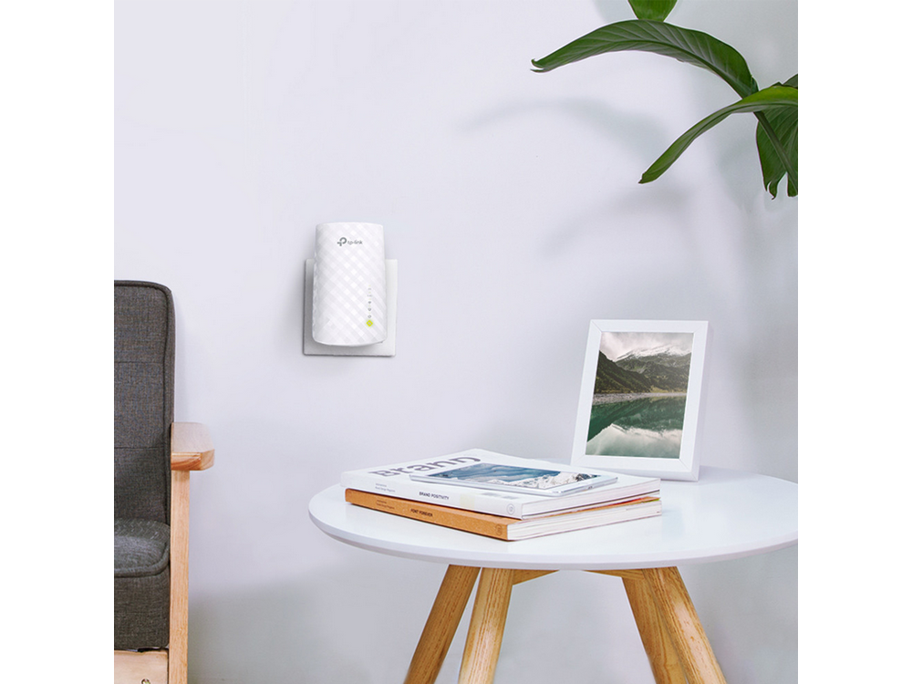 Un repetidor WiFi blanco enchufado a una toma de corriente, con una mesa y una foto.