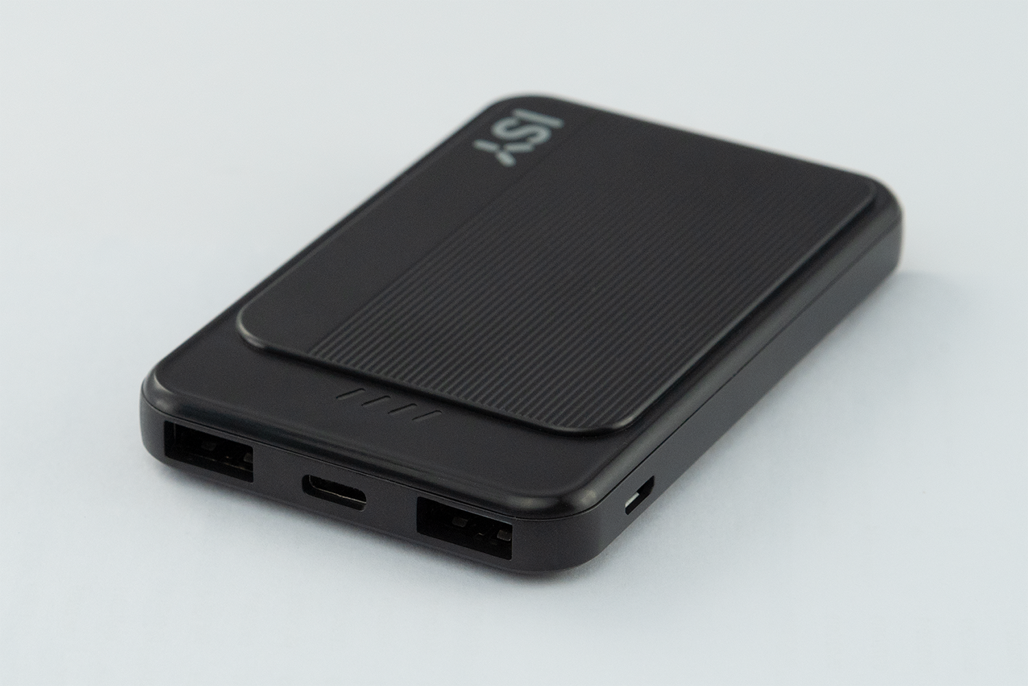 A black power bank with a textured panel and ports. The power bank is on a white surface.