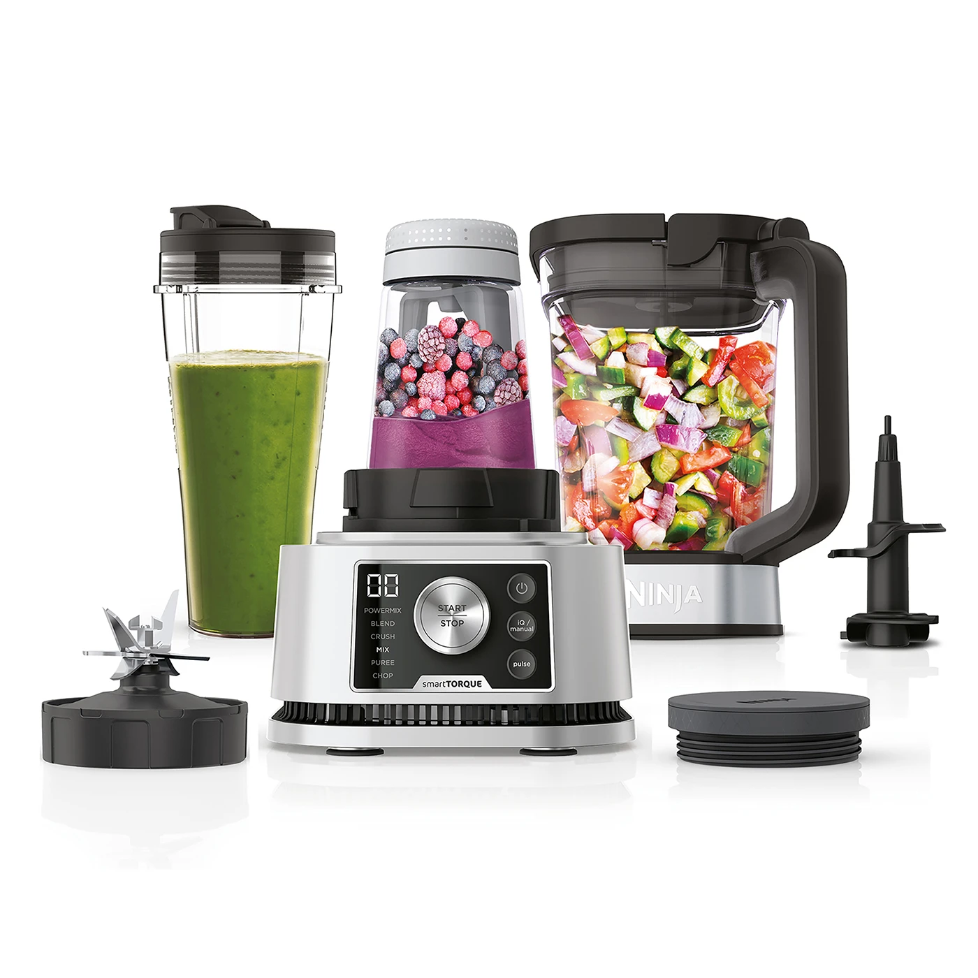 Ein Ninja-Blender-Set mit verschiedenen Behältern, Klingen und einem Sockel. Ein Behälter hat einen grünen Smoothie, ein anderer Beeren und einer gehacktes Gemüse.