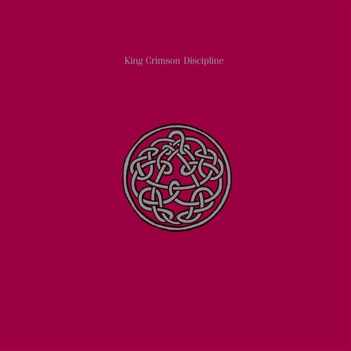 Album borító. Mély rózsaszín háttér, 'King Crimson Discipline' szöveggel. Egy kör alakú csomó minta középen.