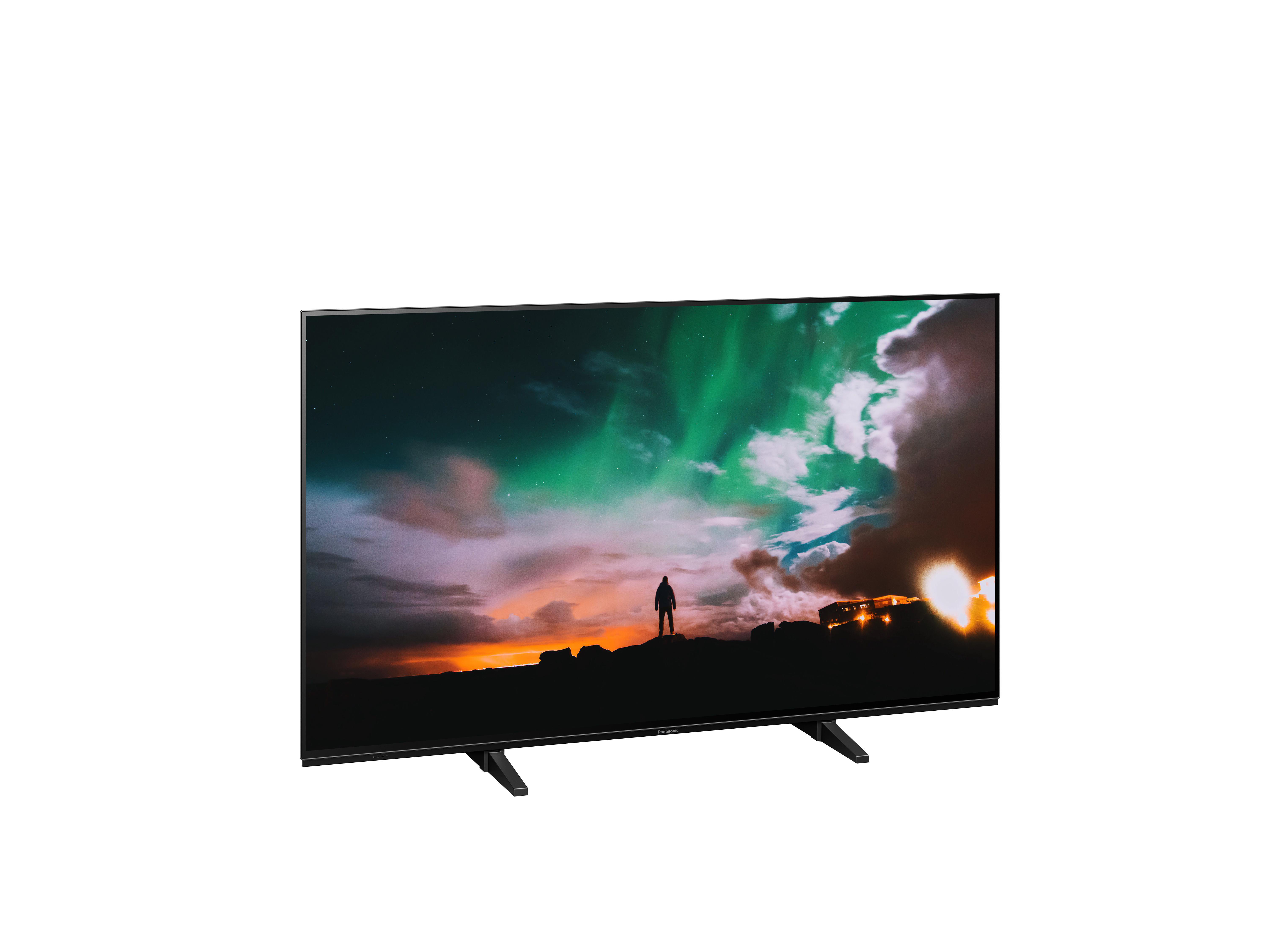 Großer Flachbildfernseher, der einen bunten Himmel mit einer Personensilhouette zeigt.