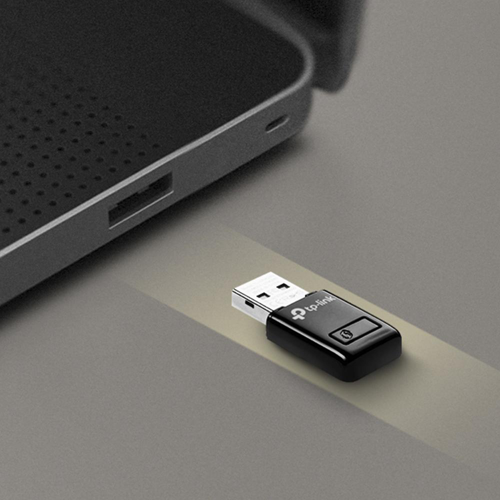 Schwarzer USB-WLAN-Adapter, der an einen Laptop angeschlossen ist. Adapter auf grauer Oberfläche.