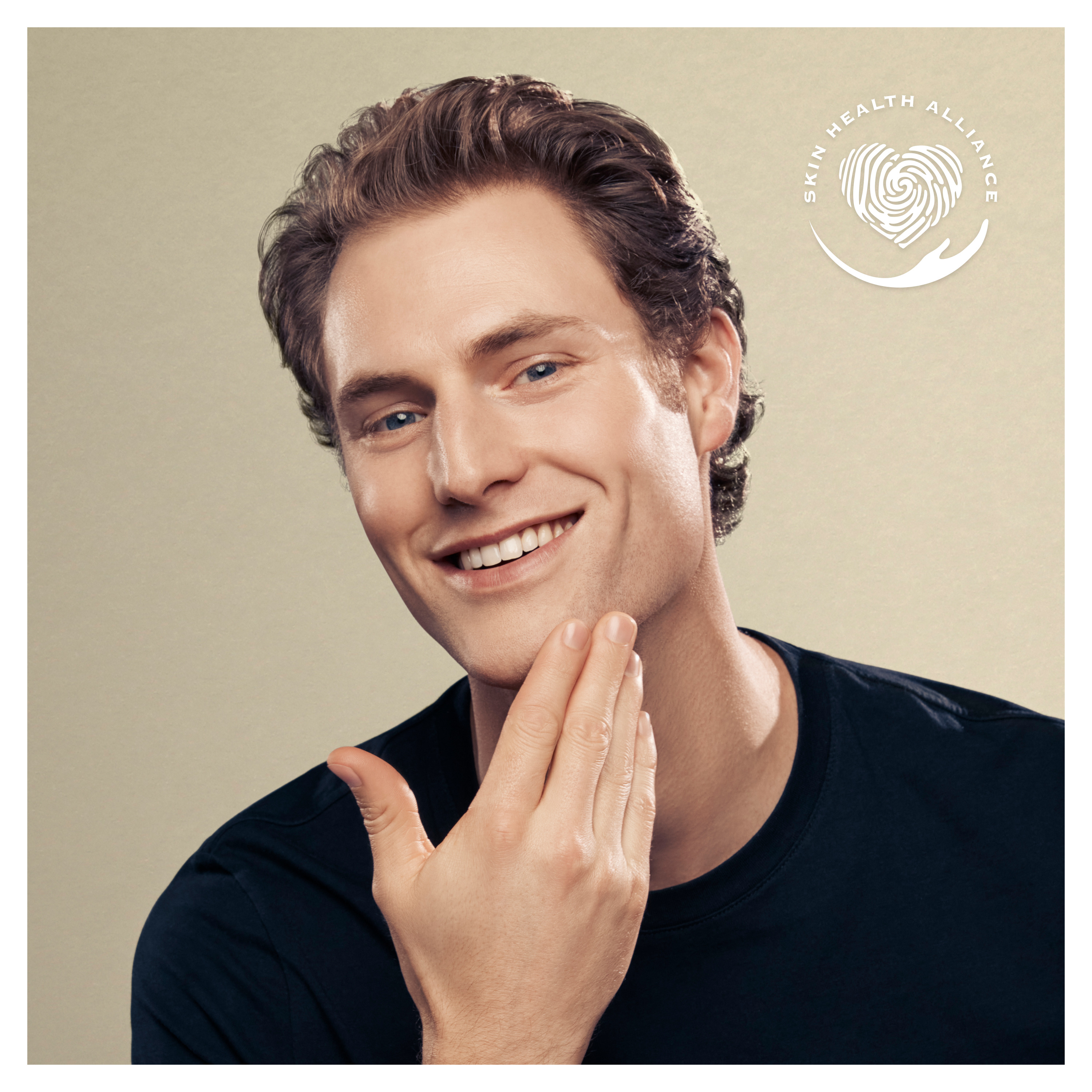 Un homme souriant se touchant la mâchoire, avec un logo d'alliance pour la santé de la peau en haut à droite.