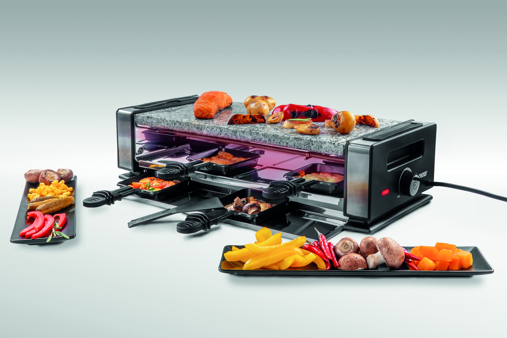 Raclette-Grill mit Speisen, einschließlich Gemüse und Käse. Ein schwarzer Drehknopf rechts.
