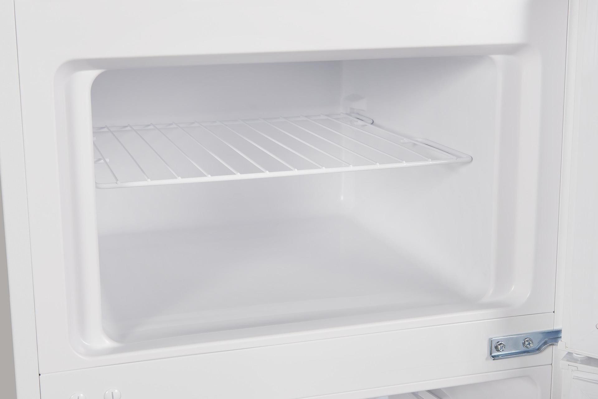 Leerer weißer Kühlschrankinnenraum mit Drahtregal. Sauberes, helles und schlichtes Design.
