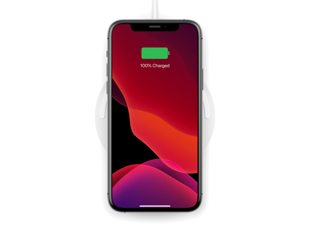 Smartphone cargando en cargador inalámbrico. 100% cargado en pantalla.
