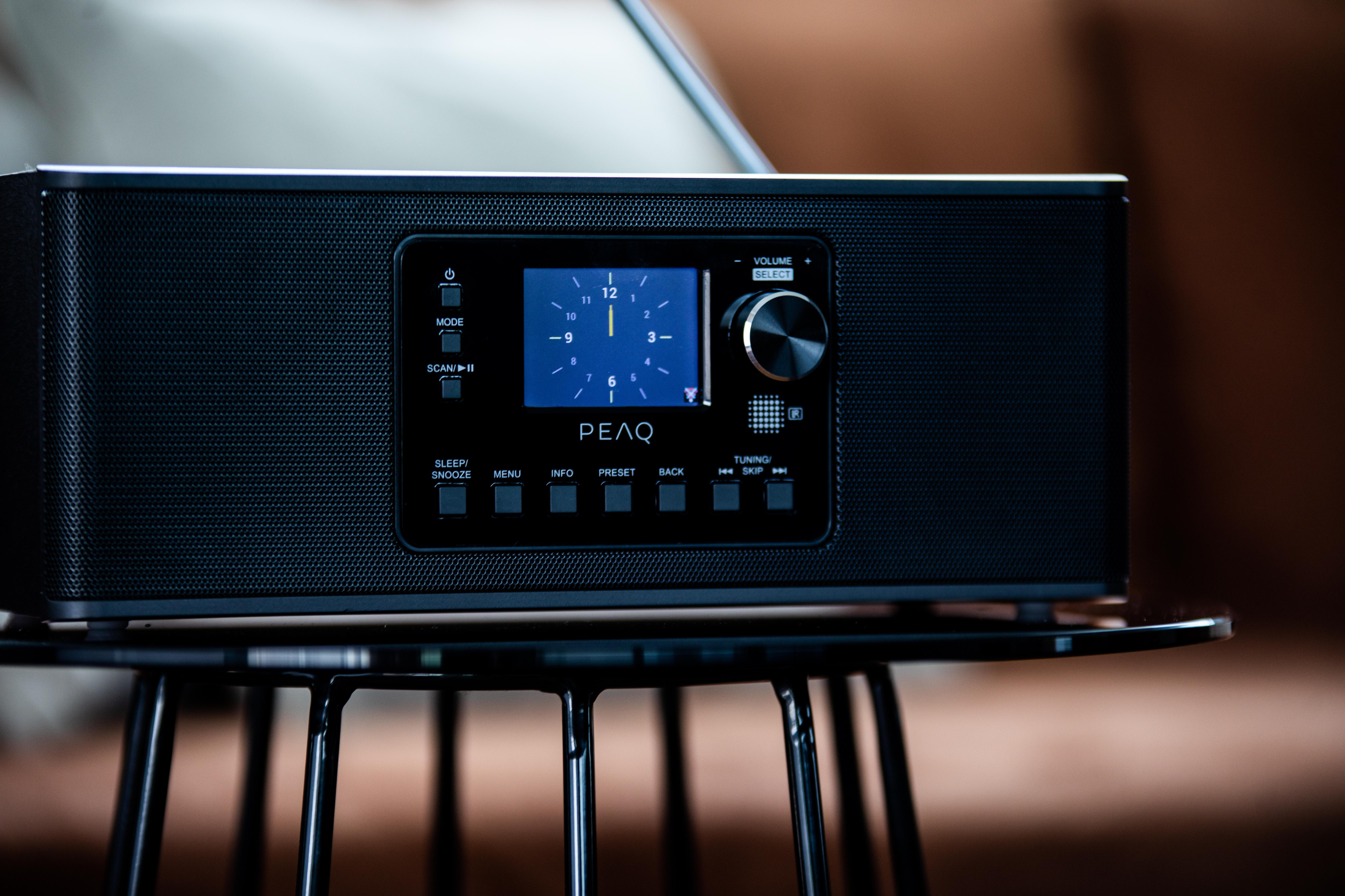 Ein schwarzes PEAQ-Radio auf einem schwarzen Metalltisch in einem Raum.