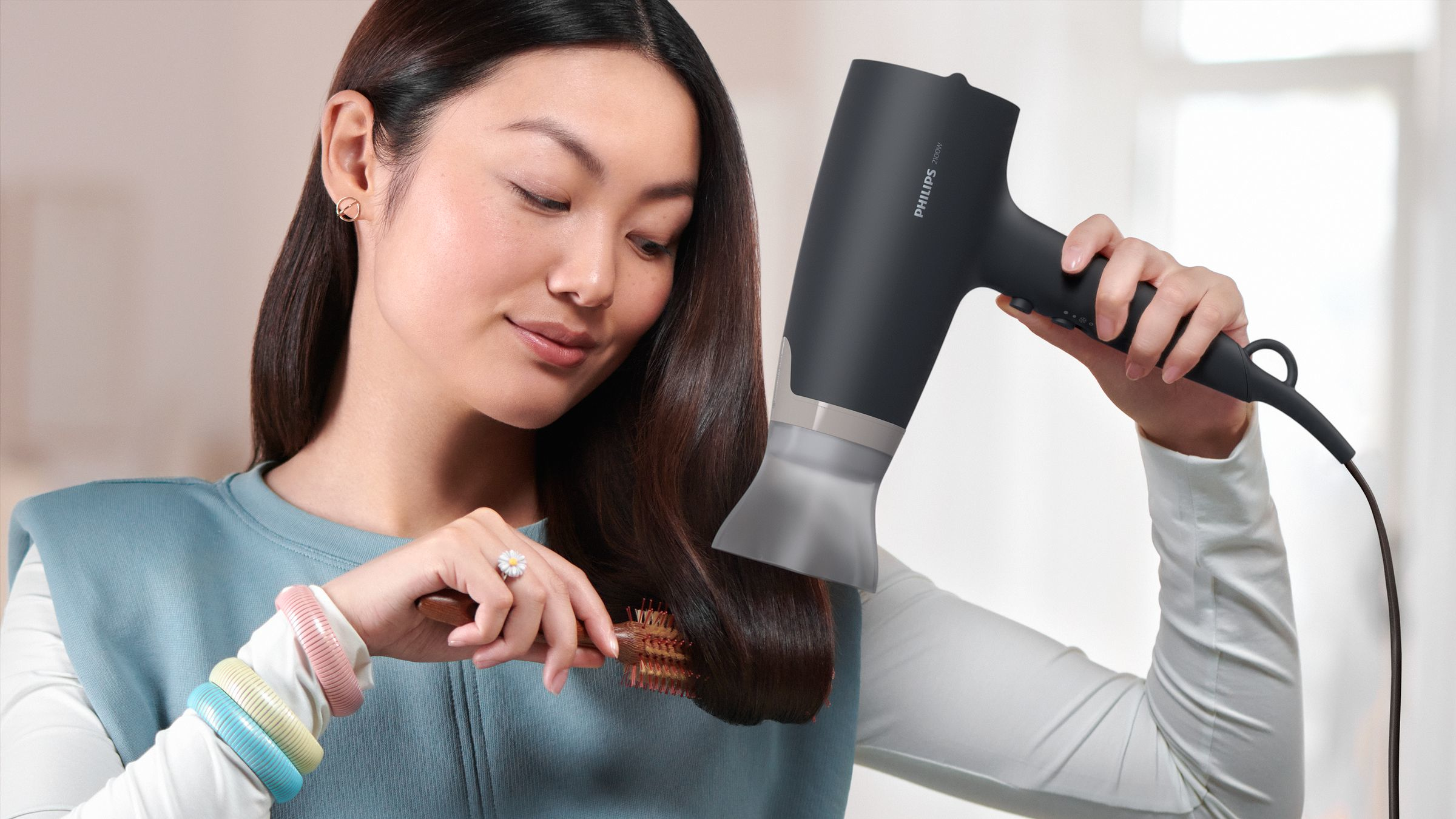 Woman using a hair dryer and brushing her hair.