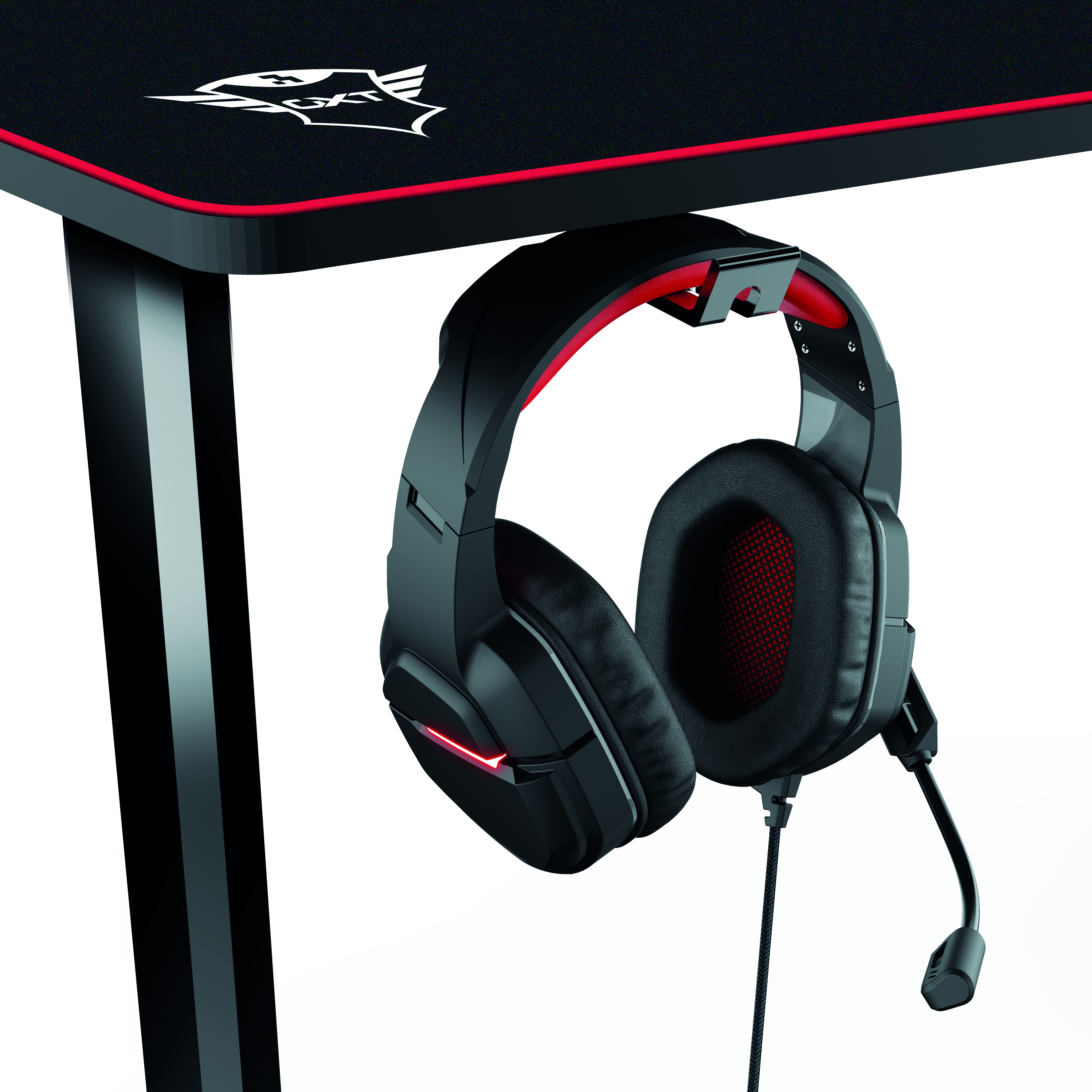 Ein schwarzes Gaming-Headset hängt an einem schwarz-roten Schreibtisch. Weißer Hintergrund.