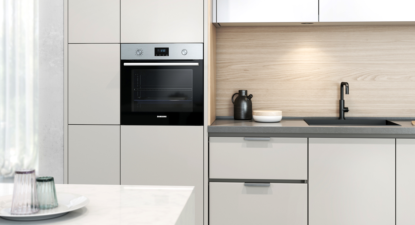 A kitchen with white cabinets, a black oven, and a dark sink.