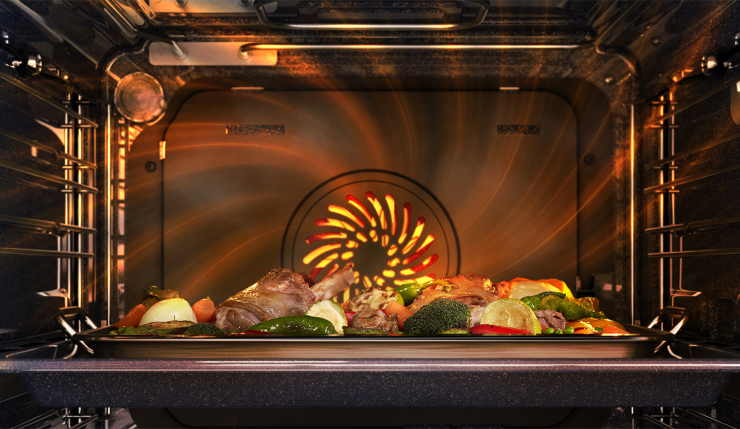 Oven interior with roasted vegetables and meat on a tray, fan heating.