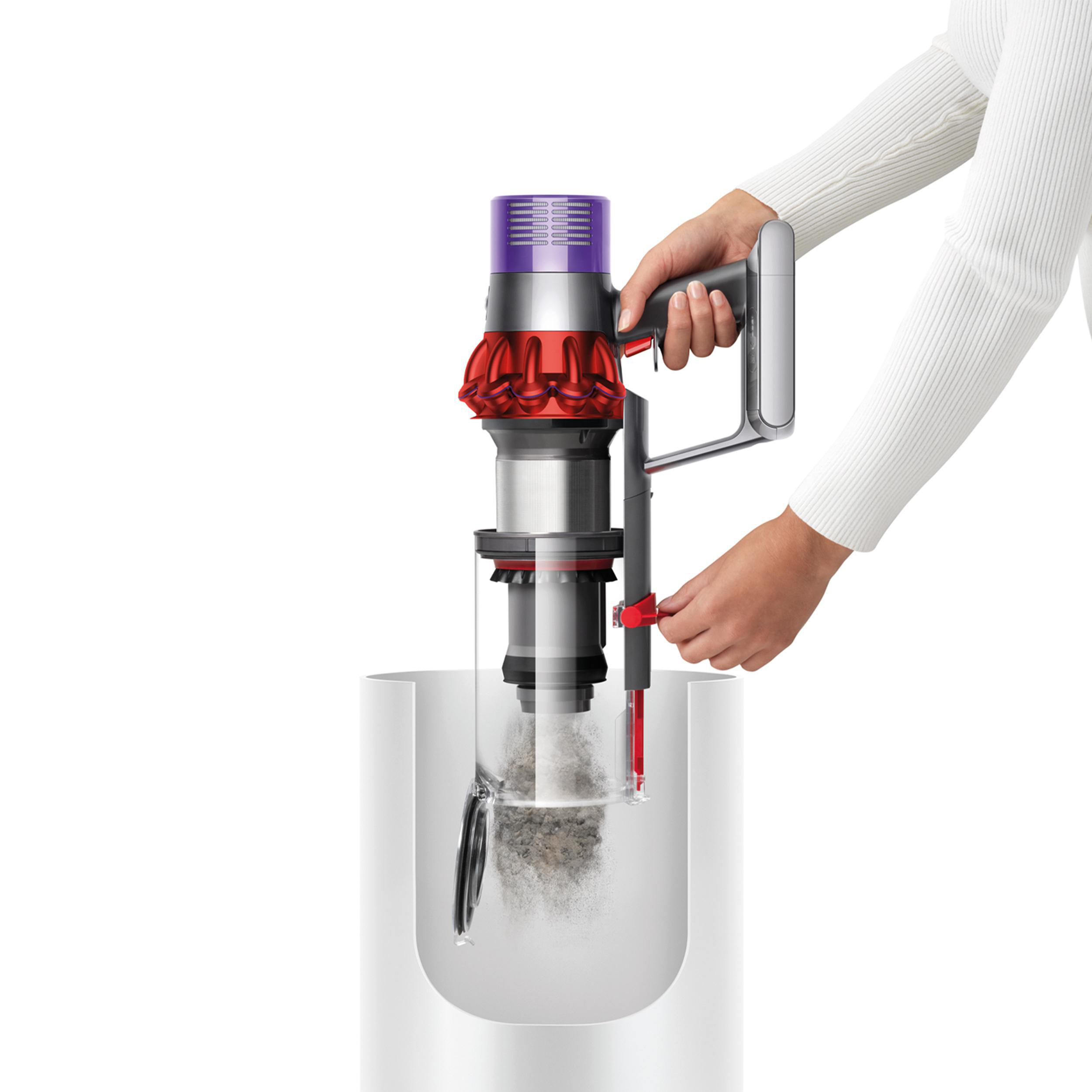 Eine Person entleert einen Dyson-Staubsauger in einen weißen Behälter.