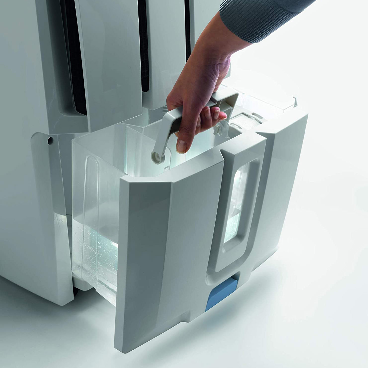 Una mano estrae un serbatoio dell'acqua da un deumidificatore bianco. Il serbatoio è per lo più trasparente.