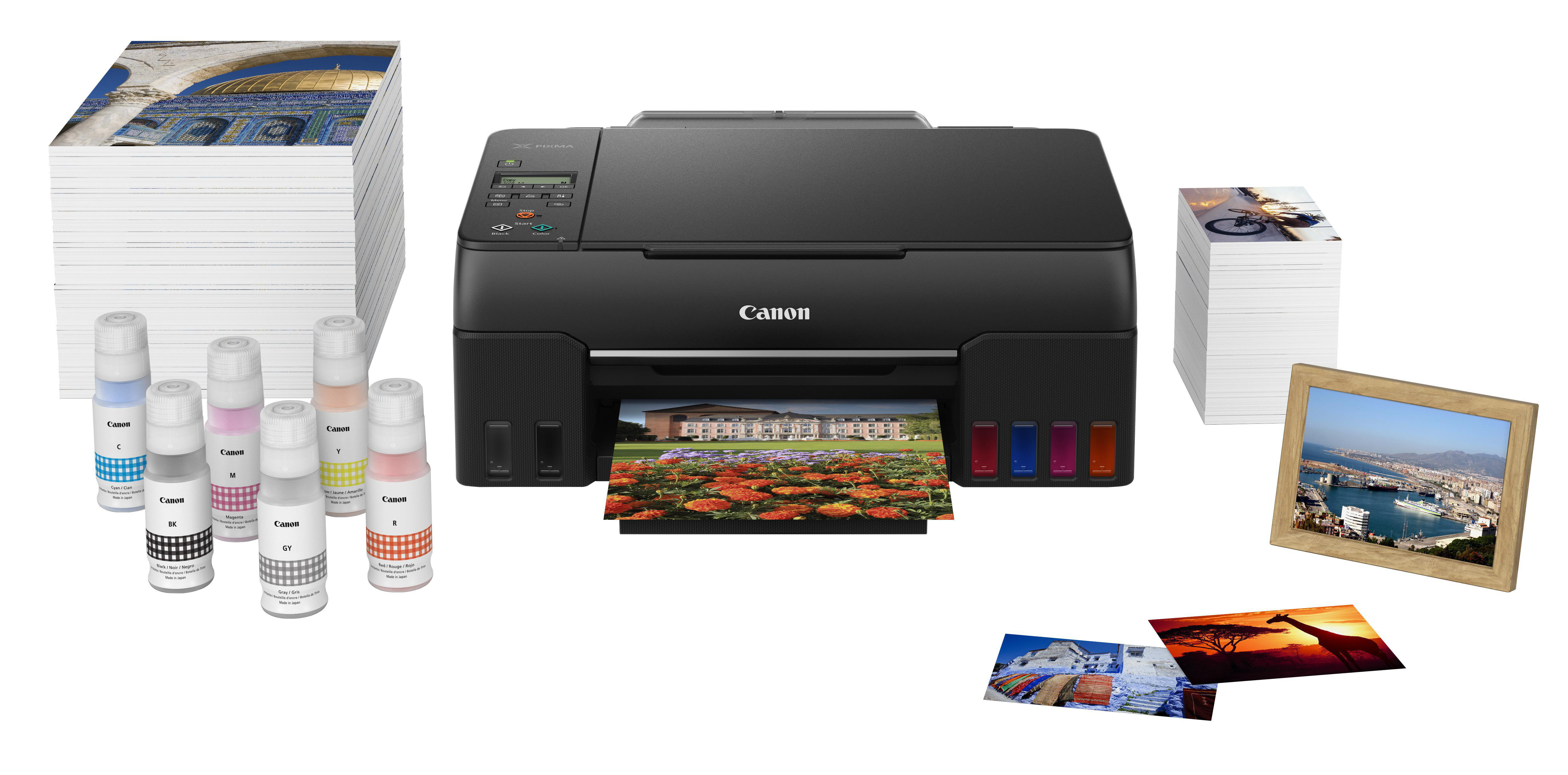 Ein Canon-Drucker, der ein Foto druckt, mit Tintenflaschen und Ausdrucken drumherum.
