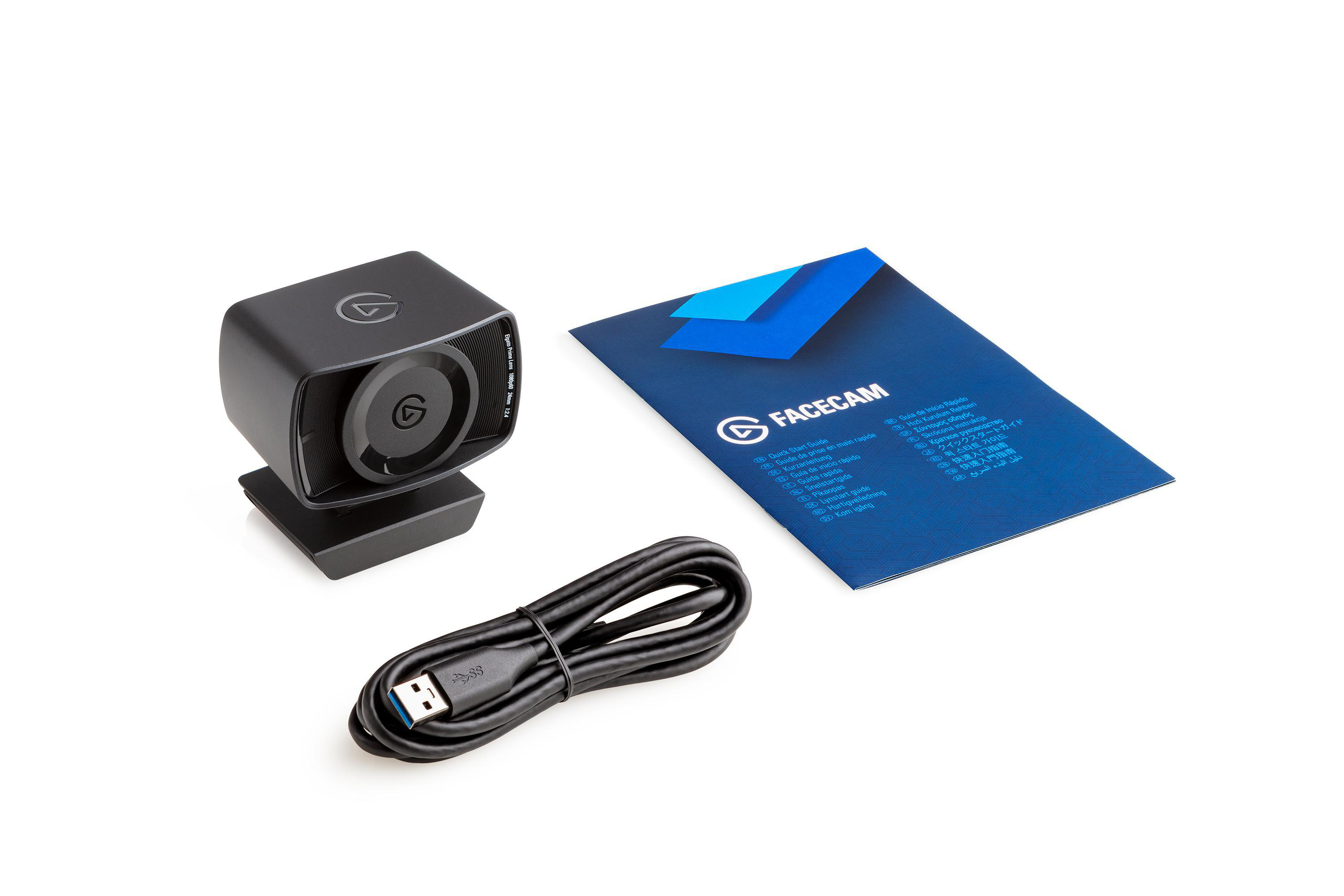 Eine schwarze Webcam, ein Kabel und eine blaue Facecam-Anleitung liegen auf Weiß.