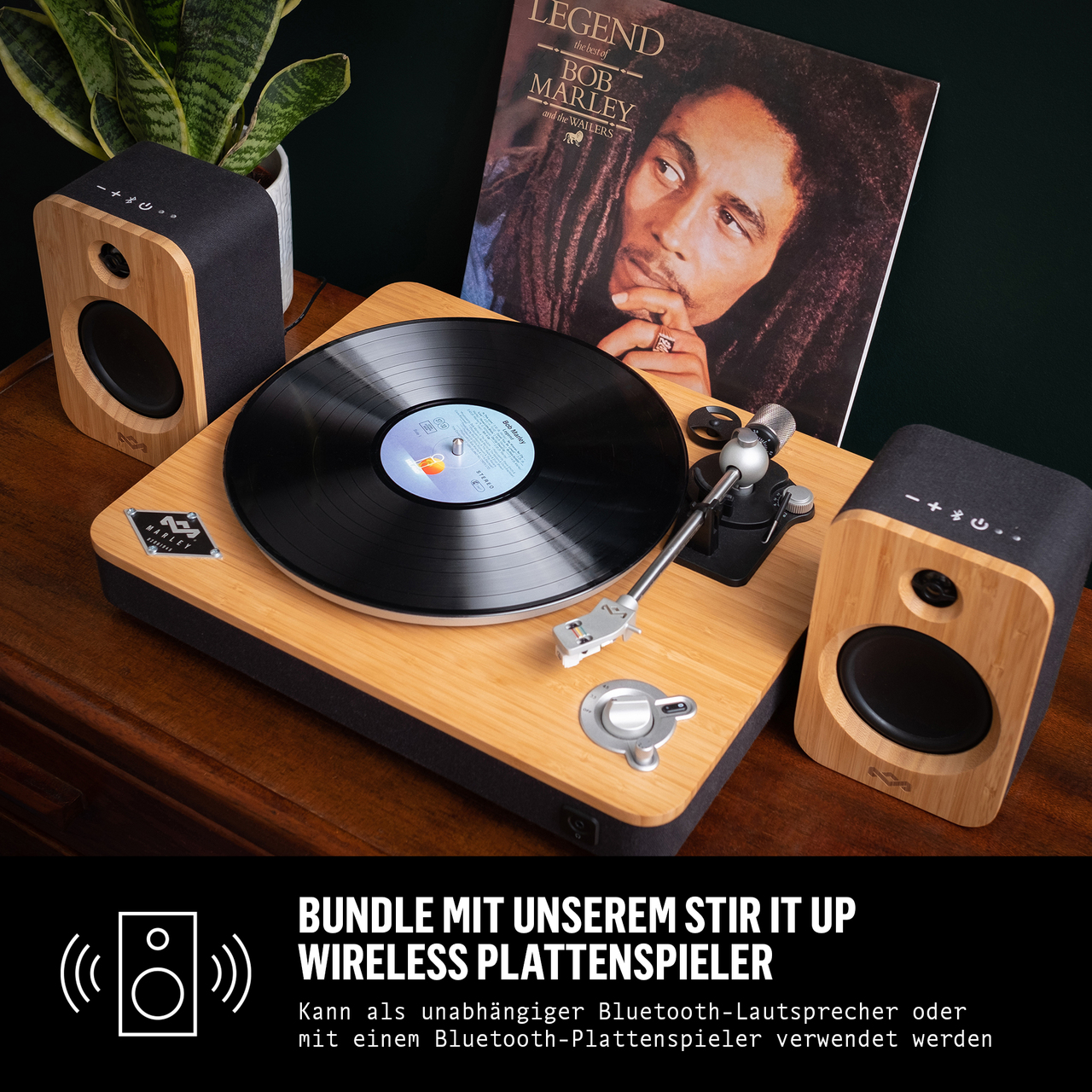 Un giradischi in legno con un disco, altoparlanti e una copertina dell'album di Bob Marley su un tavolo.