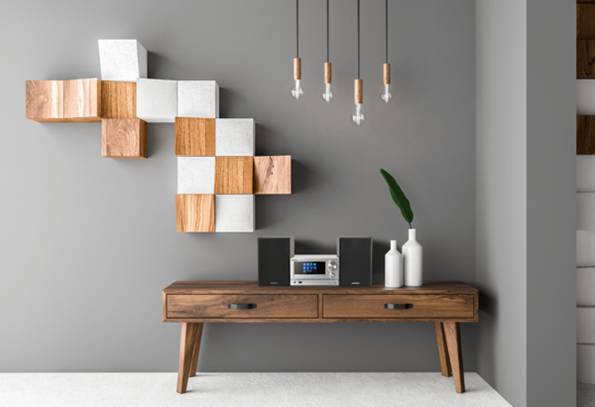 Ein Wohnzimmerszene mit einem Holzschrank, Lautsprechern und einer grauen Wand mit Dekoration.