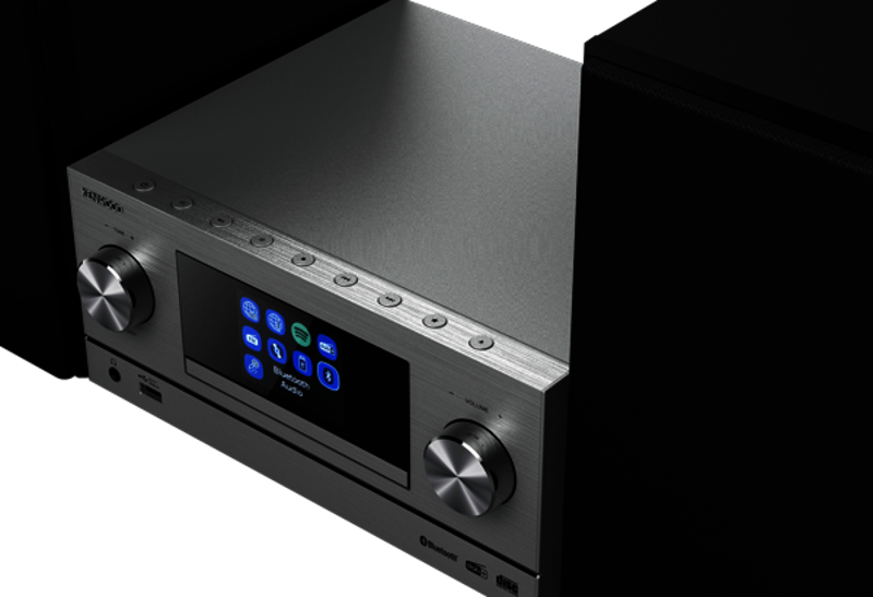 Silbernes Audiosystem mit Bildschirm und Knöpfen, zwischen schwarzen Lautsprechern.