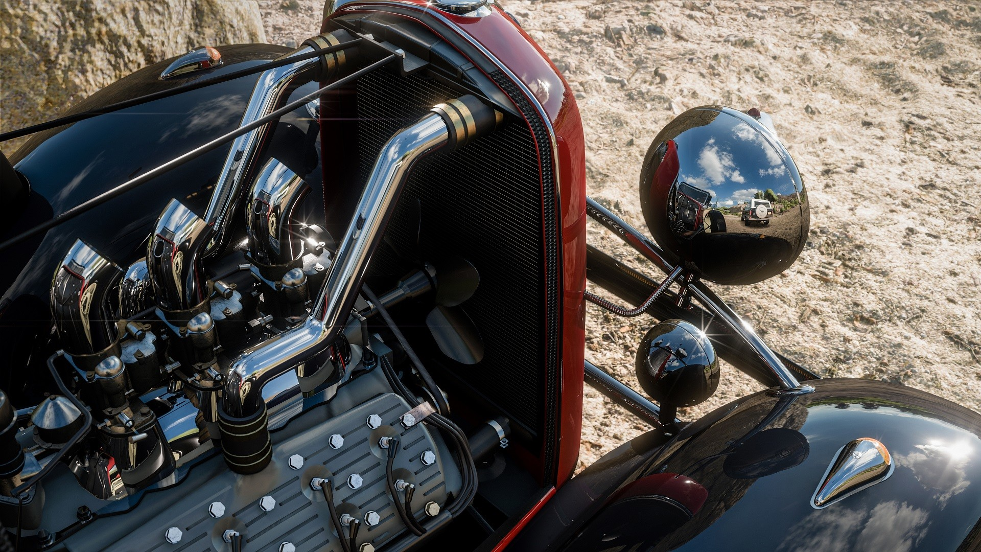 Nahaufnahme des Motors eines Oldtimers. Chromrohre und eine rote Karosserie sind sichtbar.