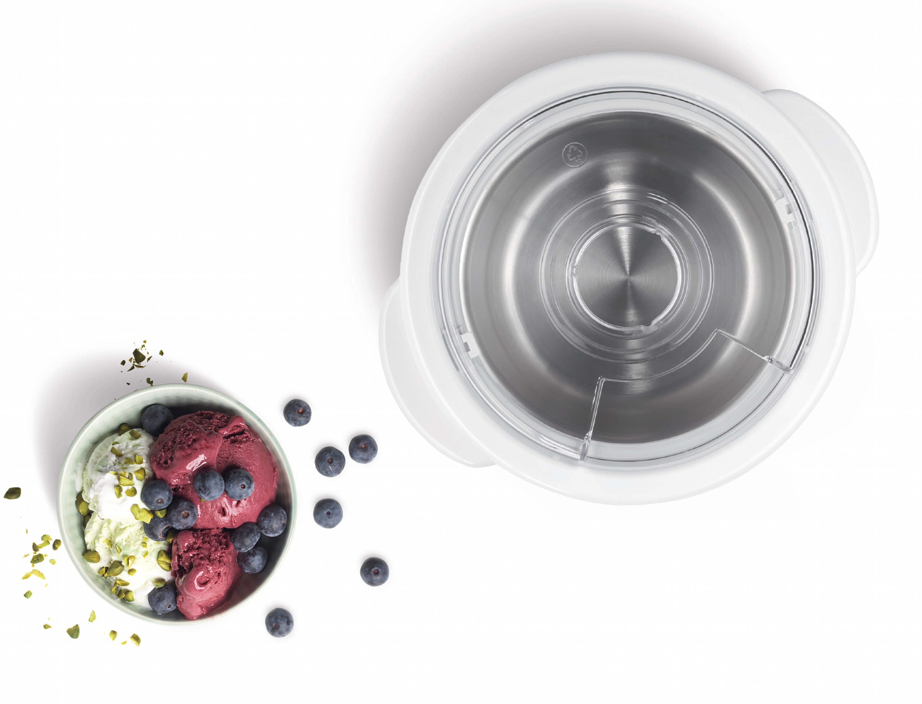 Eisbecher mit Pistazien und Blaubeeren neben einer Eismaschine.