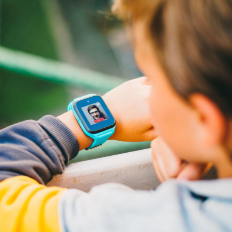 Un garçon avec une montre intelligente montrant le visage d'une personne lors d'un appel vidéo.
