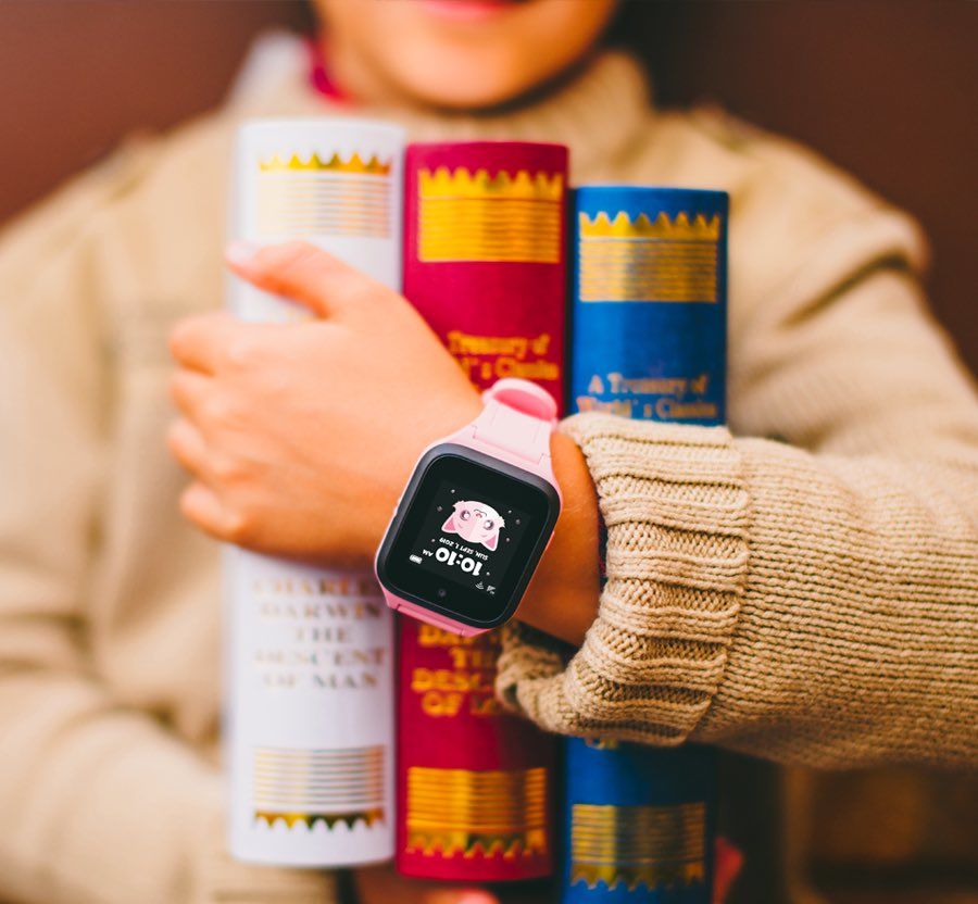 Un bambino che tiene in mano dei libri con uno smartwatch rosa al polso.