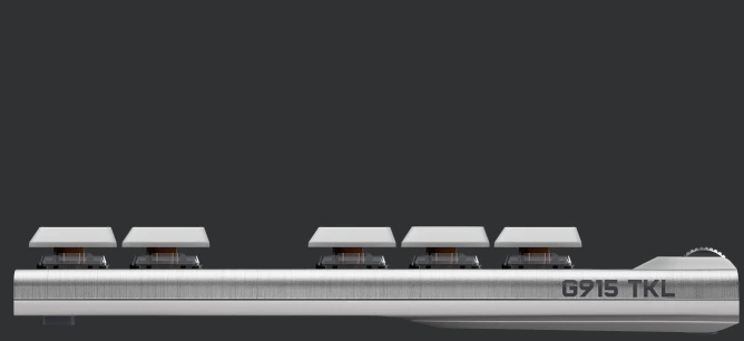 Nahaufnahme einer silbernen Tastatur. Sechs Tasten sind sichtbar, mit weißen Tastenkappen. Das Modell G915 TKL ist beschriftet.