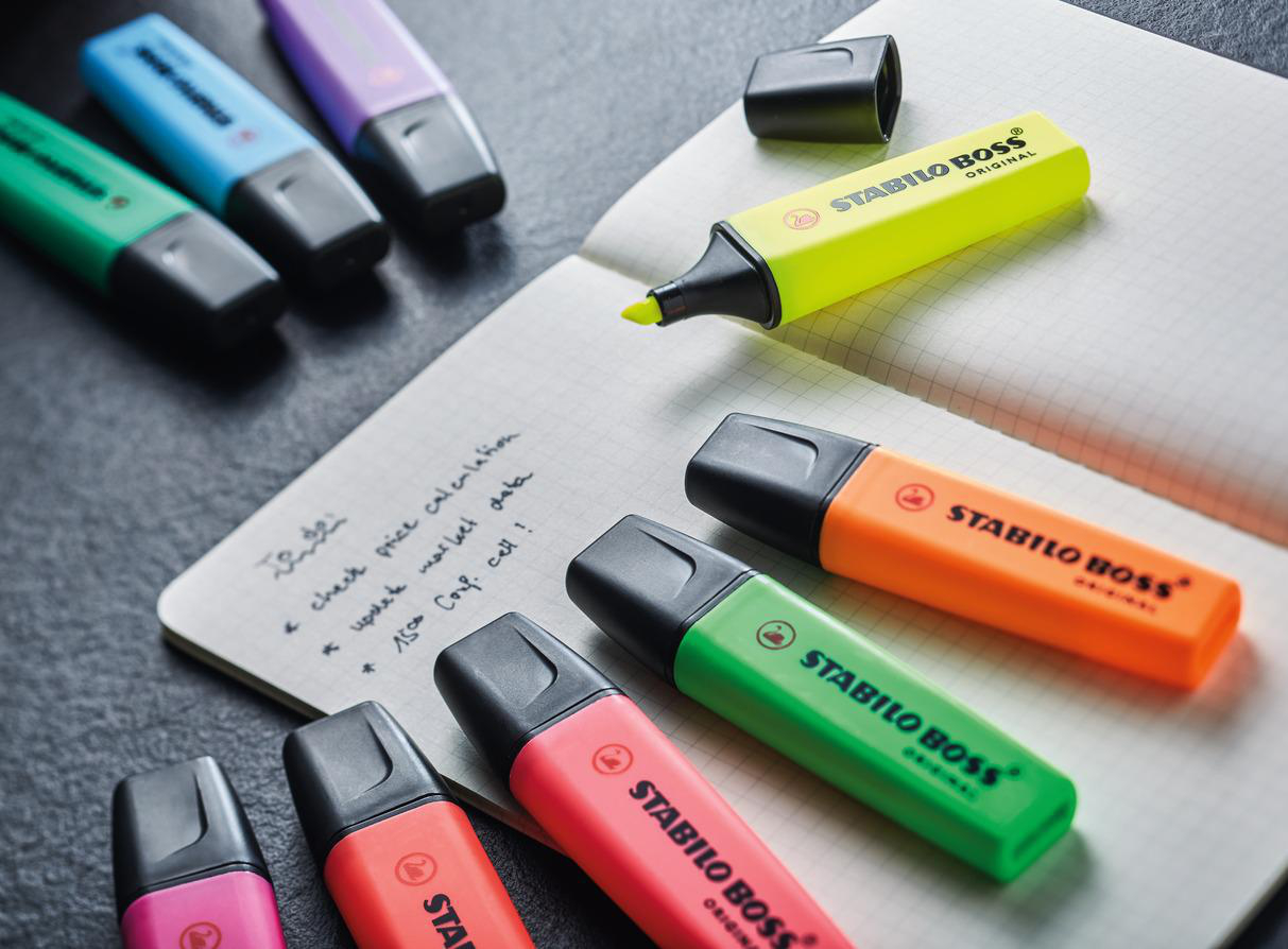 Sortiment von Stabilo Boss Textmarkern auf einem Notizblock mit handschriftlichen Notizen.