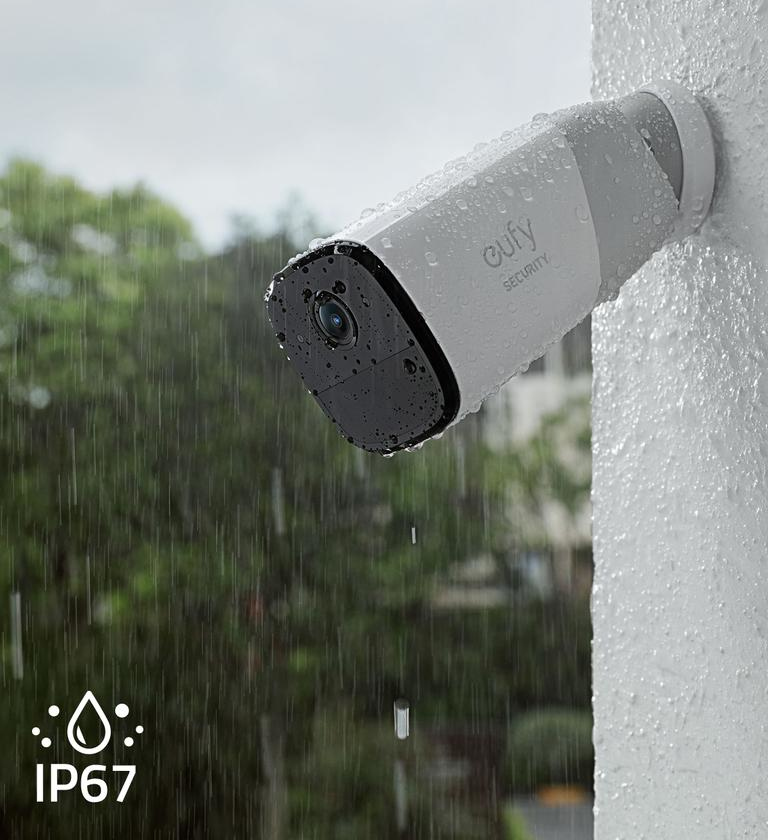 Een witte en grijze beveiligingscamera is op een muur gemonteerd.