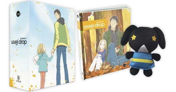Das Bild zeigt Anime-Box-Art, ein Buch und ein Plüschtier. Die Box-Art zeigt einen Mann und ein Mädchen. Das Buch zeigt einen Mann und ein Mädchen im Wald. Plüsch ist ein schwarzer Hund.